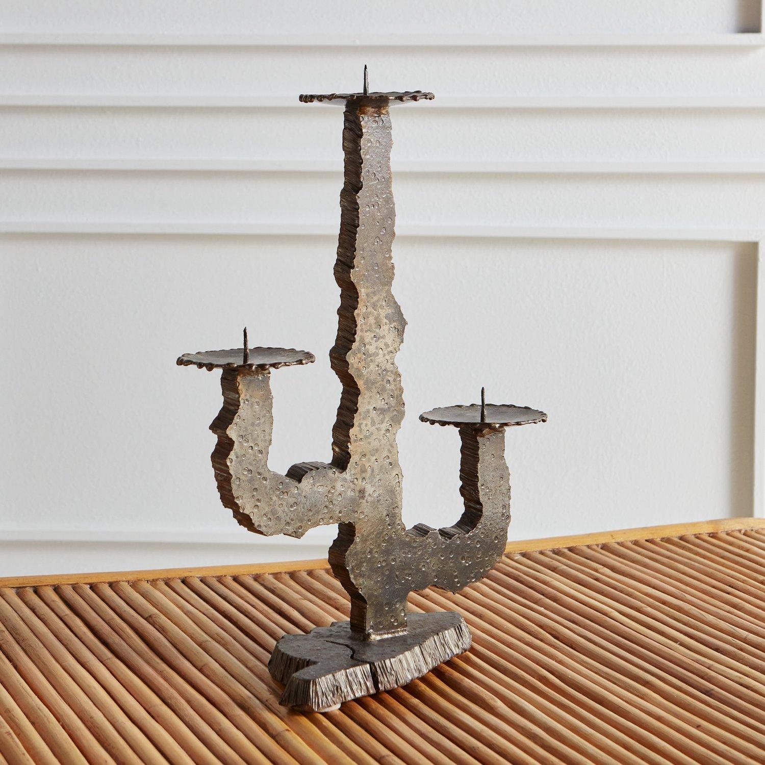 A vintage Brutalist iron candle holder in a cactus shape with three arms, each of which hold a pillar candle. This piece has excellent patina and hammered textural details. Sourced in Northern Italy, 1970s.