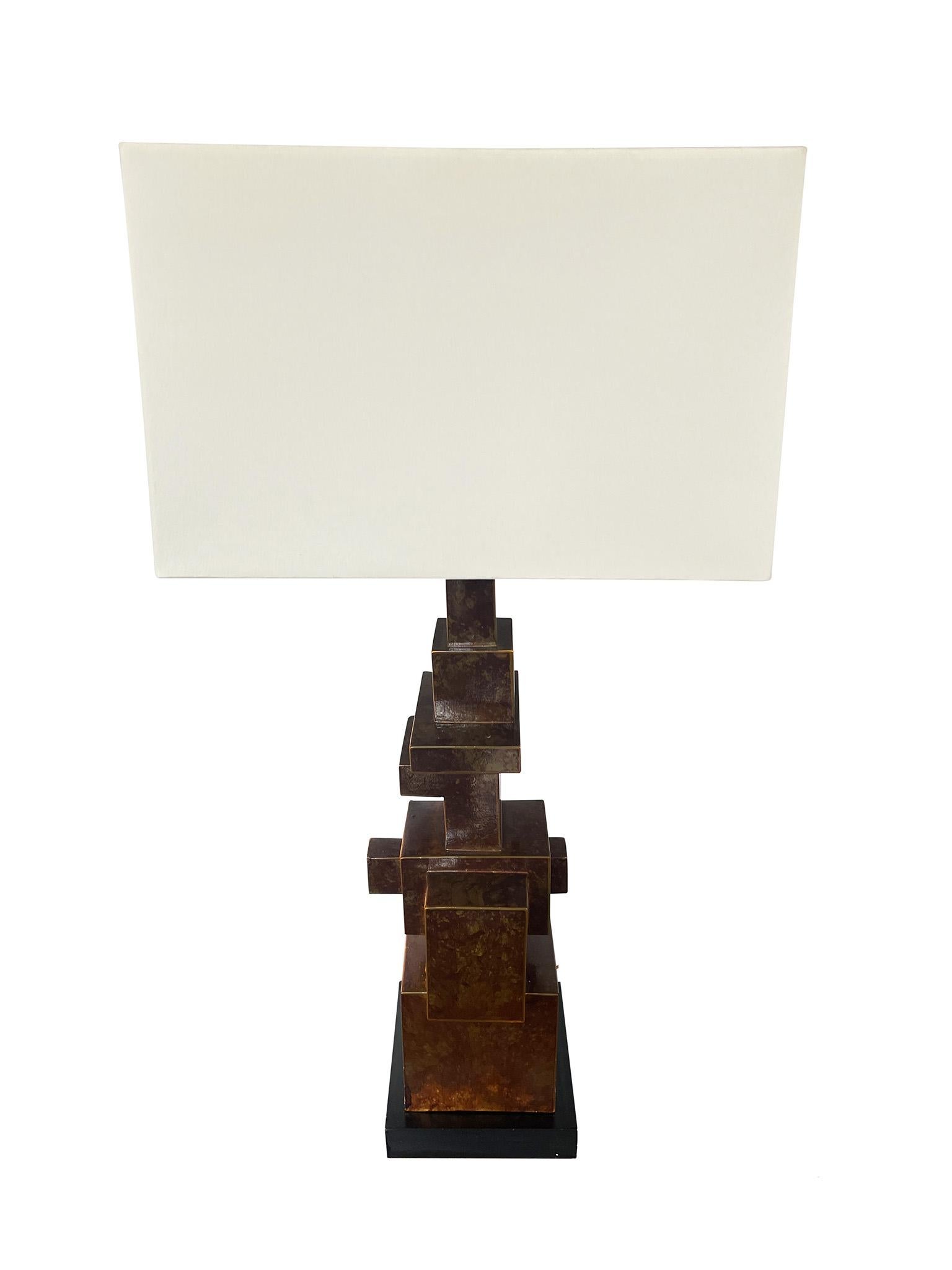 Einzigartige italienische Tischlampe im Stil des Brutalismus. Die aus patiniertem Metall mit schwarzem Holzsockel gefertigte Leuchte zeichnet sich durch ihre ungewöhnlich geformte und architektonische Komposition, die strukturierte Oberfläche und