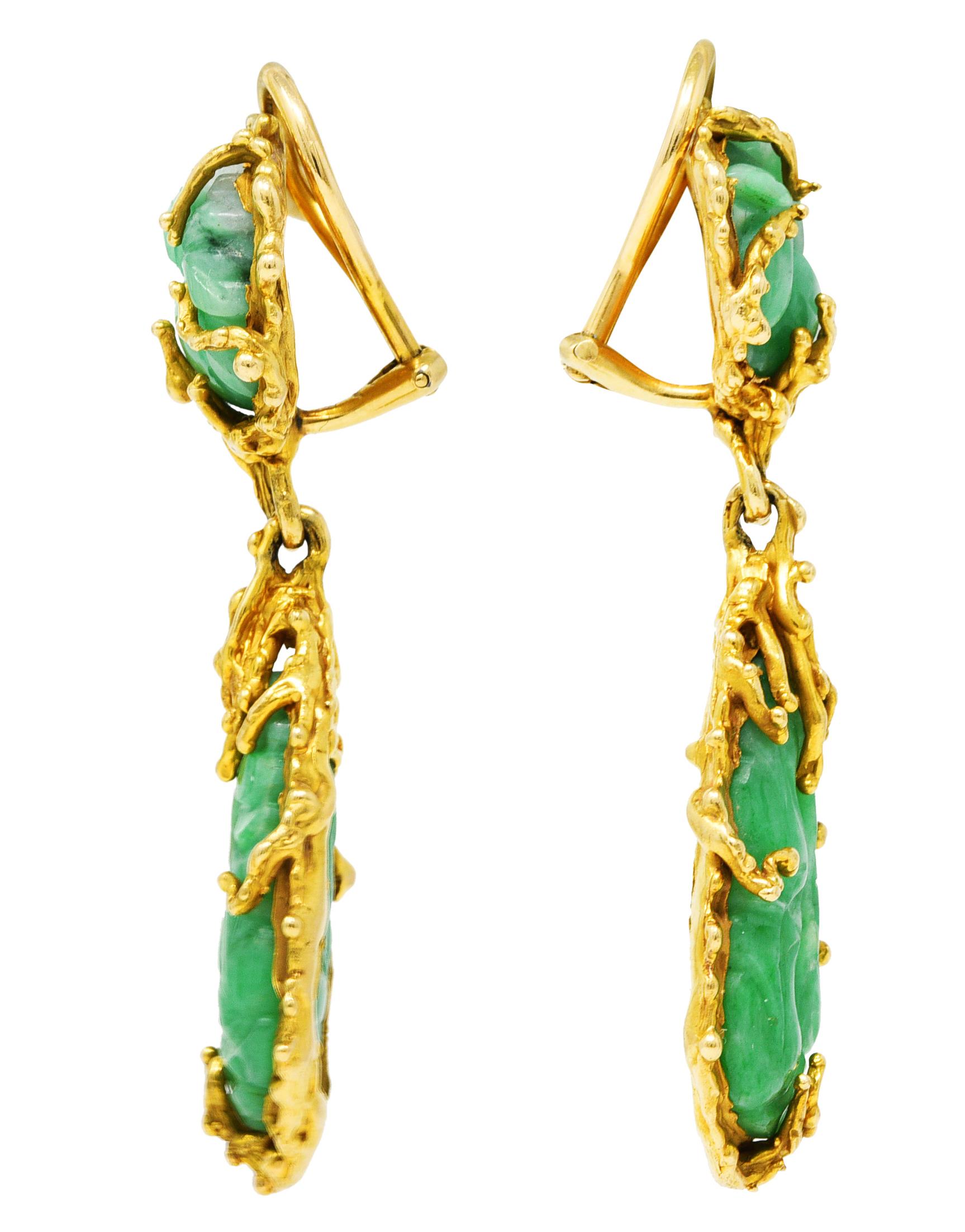 Earrings are comprised of jade surmounts and drops - carved to depict foliate and fruit. Semi-translucent green with light to medium saturation and white swirling throughout. Prong set and measuring 13.0 x 13.5 mm and 12.5 x 22.0 mm, respectively.
