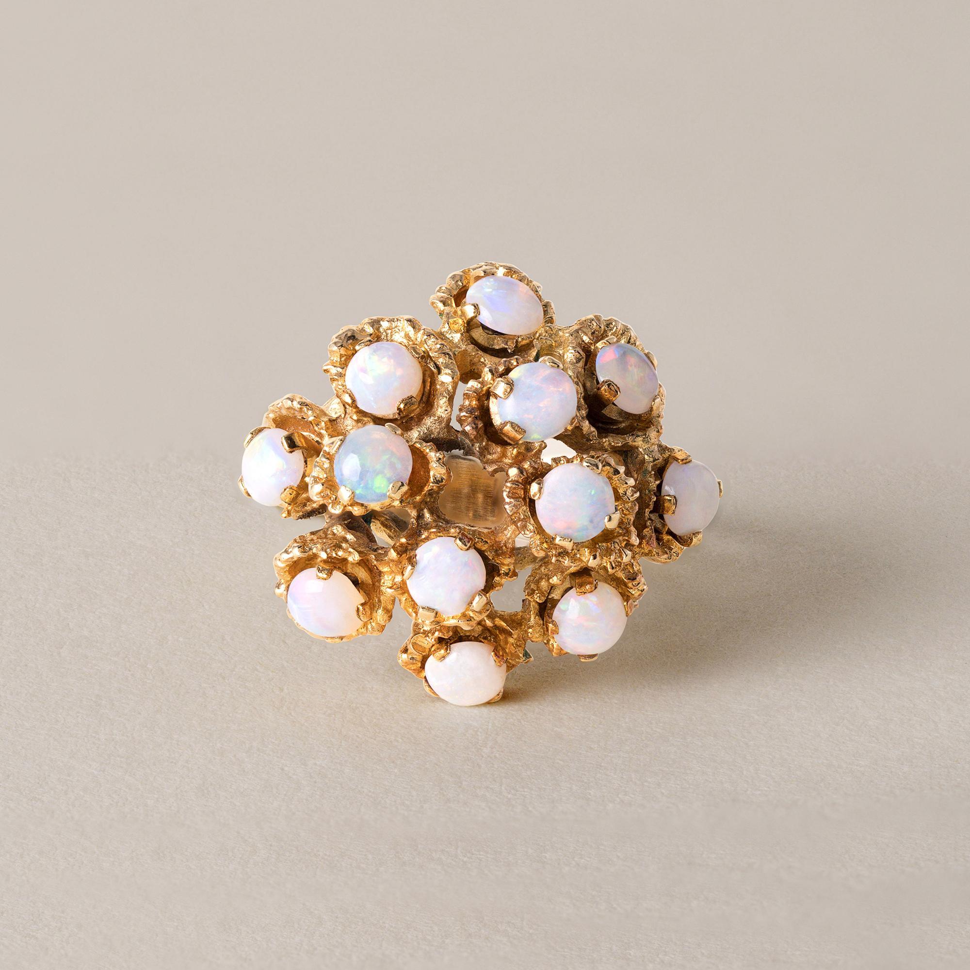 Circa 1970
12 cabochon rotondi da 3,3 mm ciascuno
Ogni opale ha un bel gioco di colori
incastonato in oro 18 carati
Stile brutalista e libero e finiture in oro testurizzato in tutta la struttura
10,4 grammi di oro 18k
750 stampato sul gambo
Anello