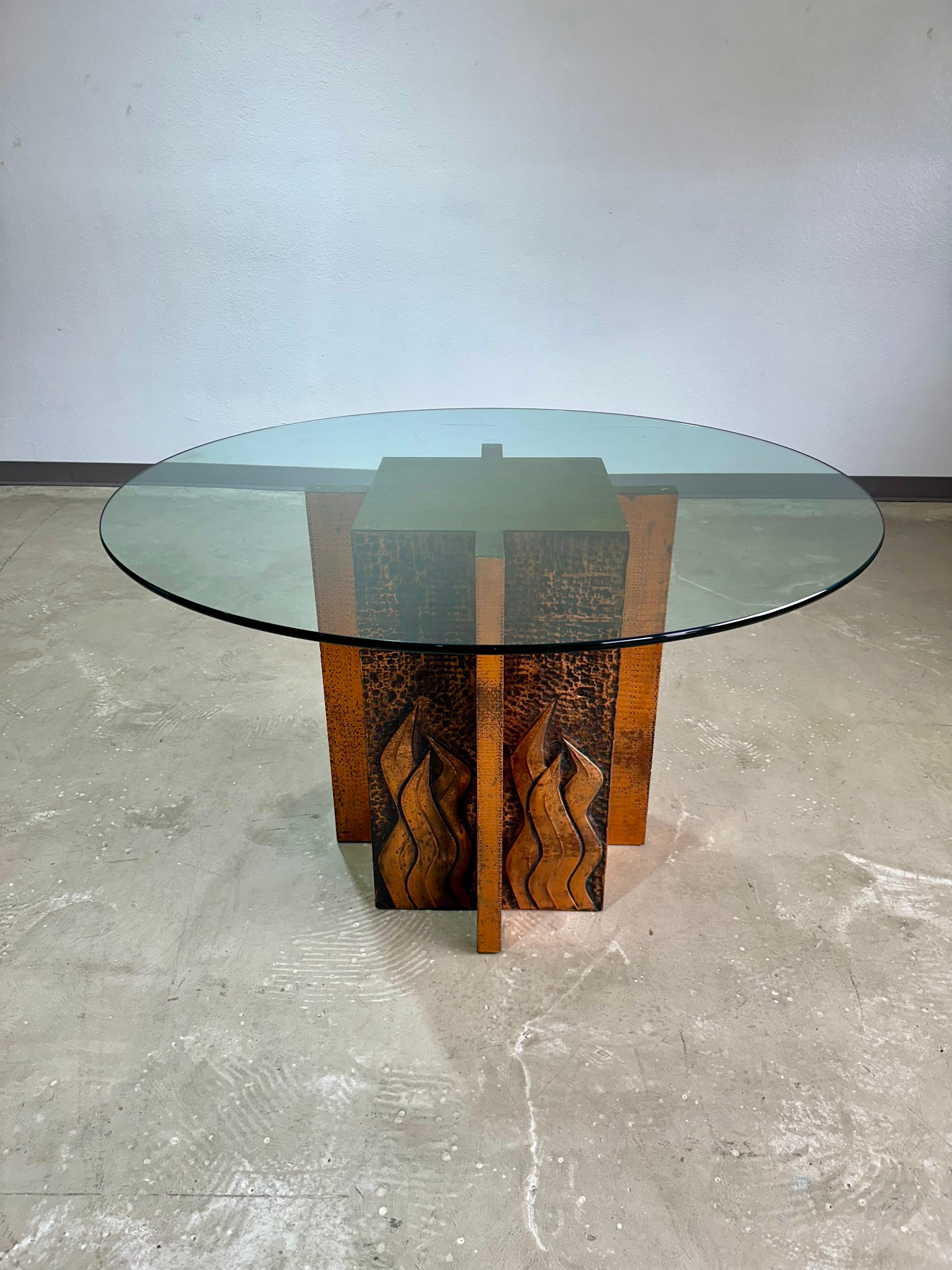 Vintage Hammered Copper Pedestal Dining Table with Glass Top in the style of Paul Evans. Maker unknown, hammered and stamped copper dimensional pedestal base. Center cross design with hammered copper, center square with stamped abstract flame
