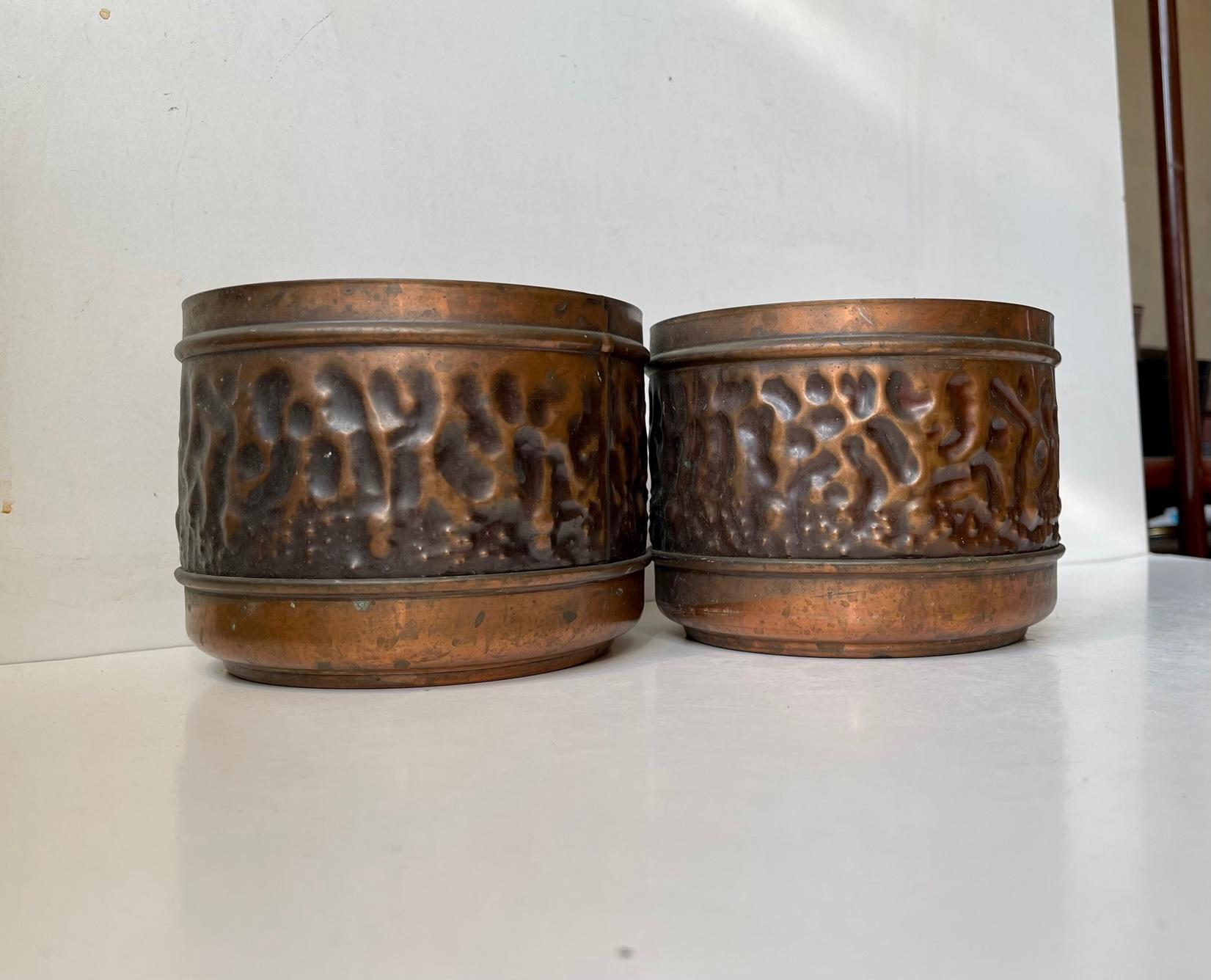 A pair of copper planters with matching patina. Embossed ina pattern that mimics the surface of the moon. Designed and manufactured by Sandnes in Norway circa 1970. Both marked with label from Sandnes. Measurements: D: 16 cm, H: 12 cm.