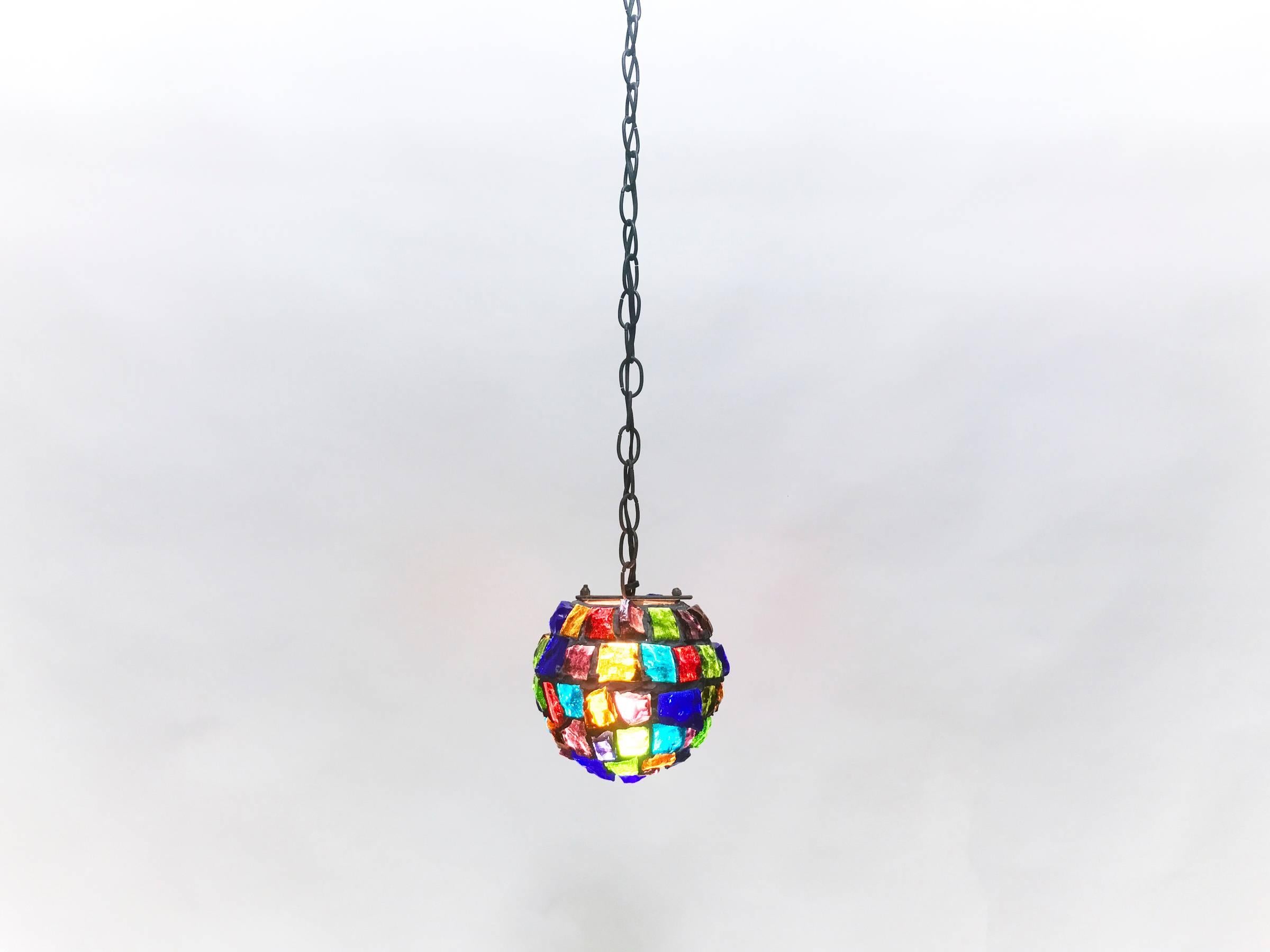 Beautiful Brutalist spherical pendant lamp with iron framework and rough multi-color glass. Diminutive in size and scale at 8 in. diameter. 11 foot chain and cord.