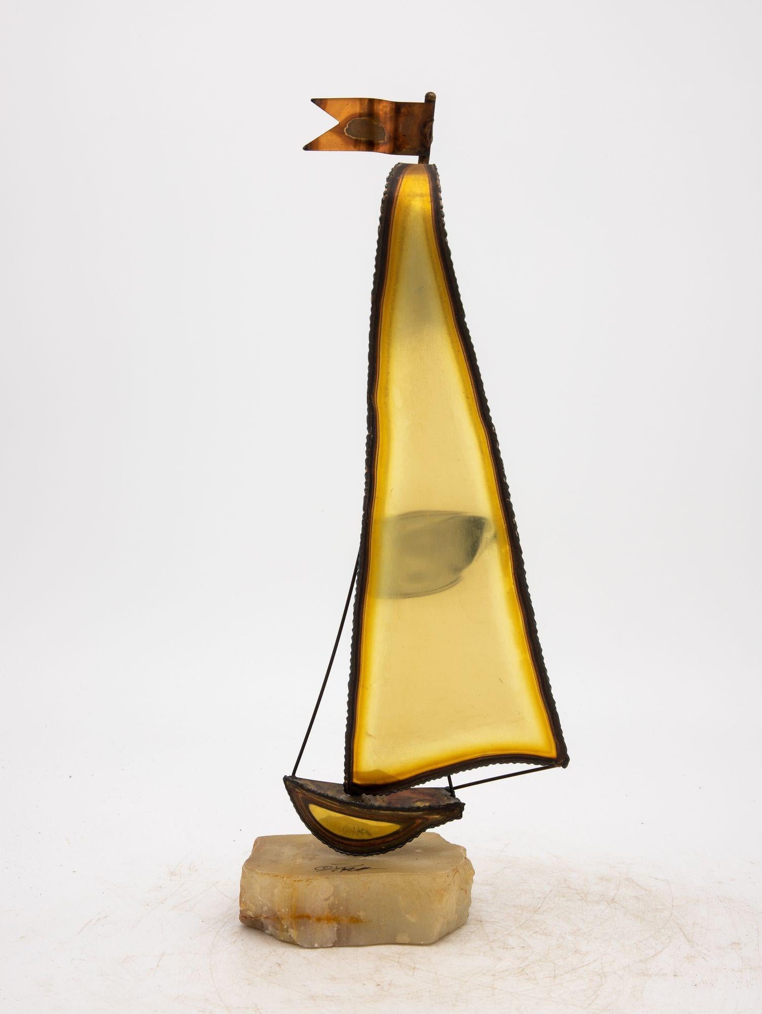A brass Brutalist-style sailboat sculpture of captivating artistry rests upon an onyx base, an iconic piece signed by DeMott. Made in the Mid 20th Century, the sculpture's sleek lines and burnished brass evoke the grace of maritime beauty. The