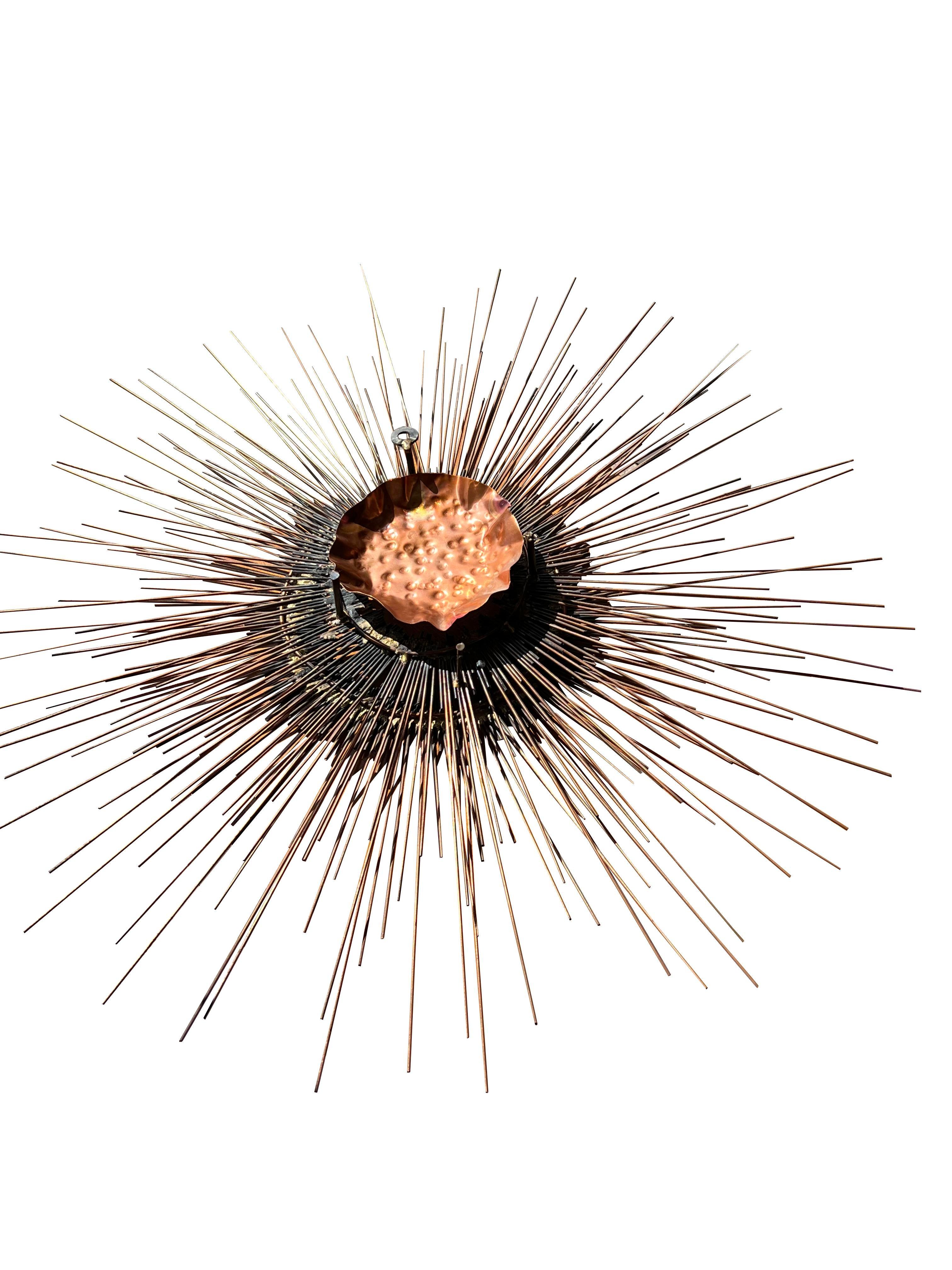 This stunning vintage sunburst wall art sculpture is a true testament to Brutalist design. Crafted in copper, the piece showcases intricate handmade details that capture the essence of the Curtis Jere style. It is bold, geometric shape and rich