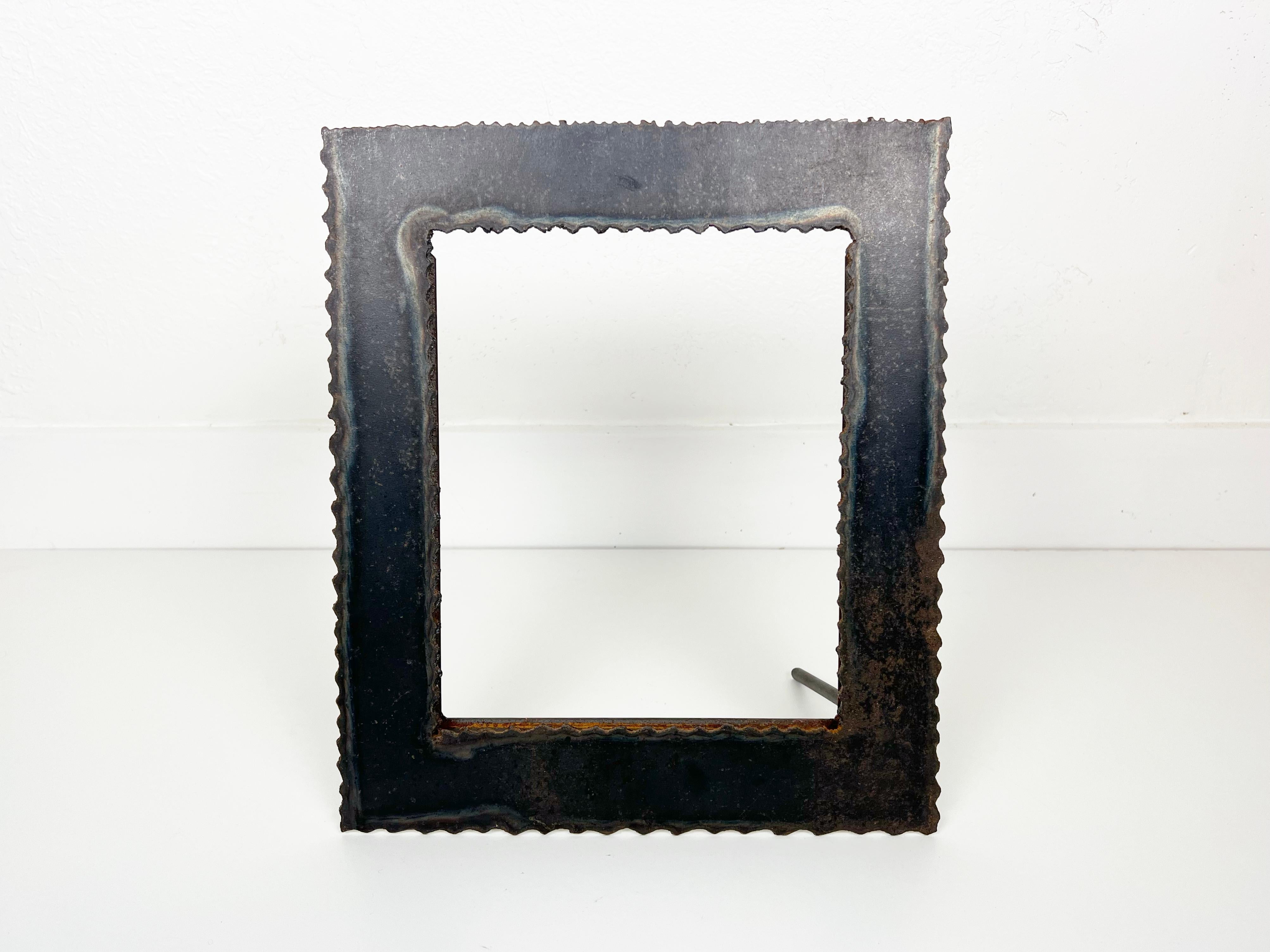 Tableau en métal brutaliste vintage fait à la main, découpé au chalumeau, fabriqué à partir d'acier de forte épaisseur. Le cadre est doté d'un support métallique qui permet de le poser sur une table à la verticale ou à l'horizontale. 

Année :