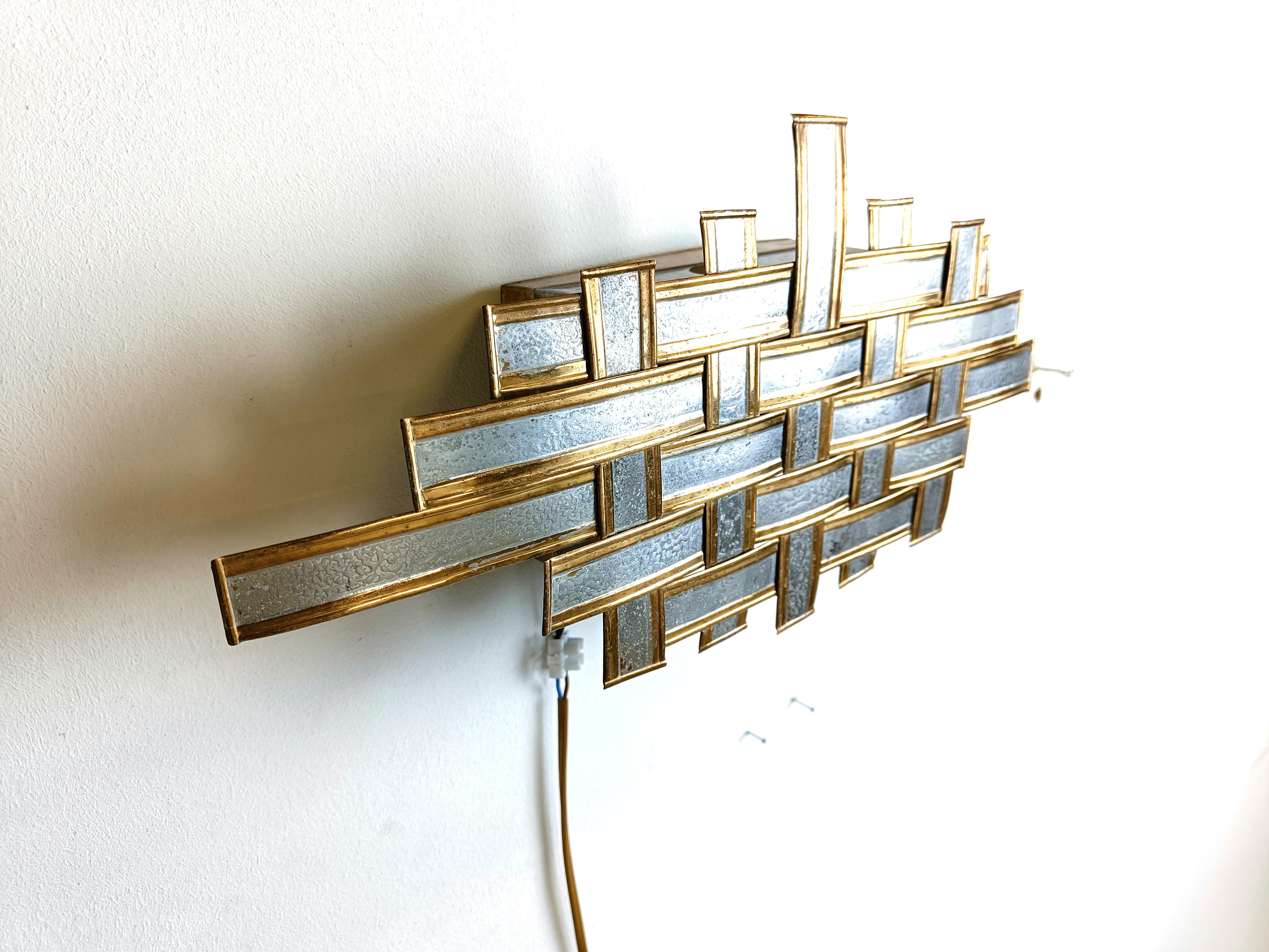 Vintage brutalist design metal wall lamp.

The lamp was made with metal strips woven into each other.

Tested and ready to use

1970s - Belgium

Dimensions:
Height: 20cm
Width: 40cm
Depth: 10cm

Ref.: 210155