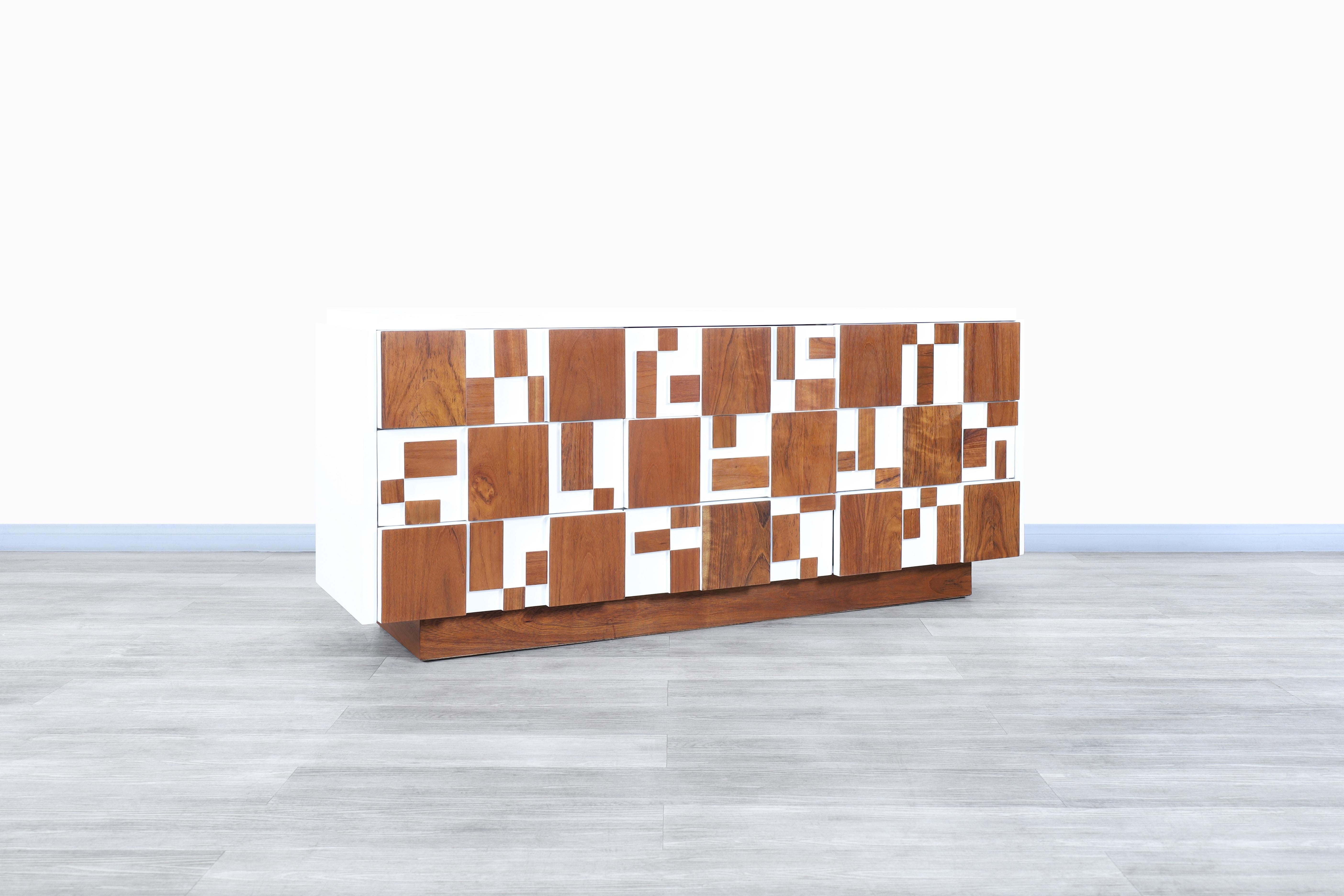 Amazing vintage brutalist walnut mosaic credenza manufactured by Lane in the United States, circa 1960s. This dresser features nine dovetail drawers, all integrated with geometric shapes on the front side. Its versatility allows it to serve as a