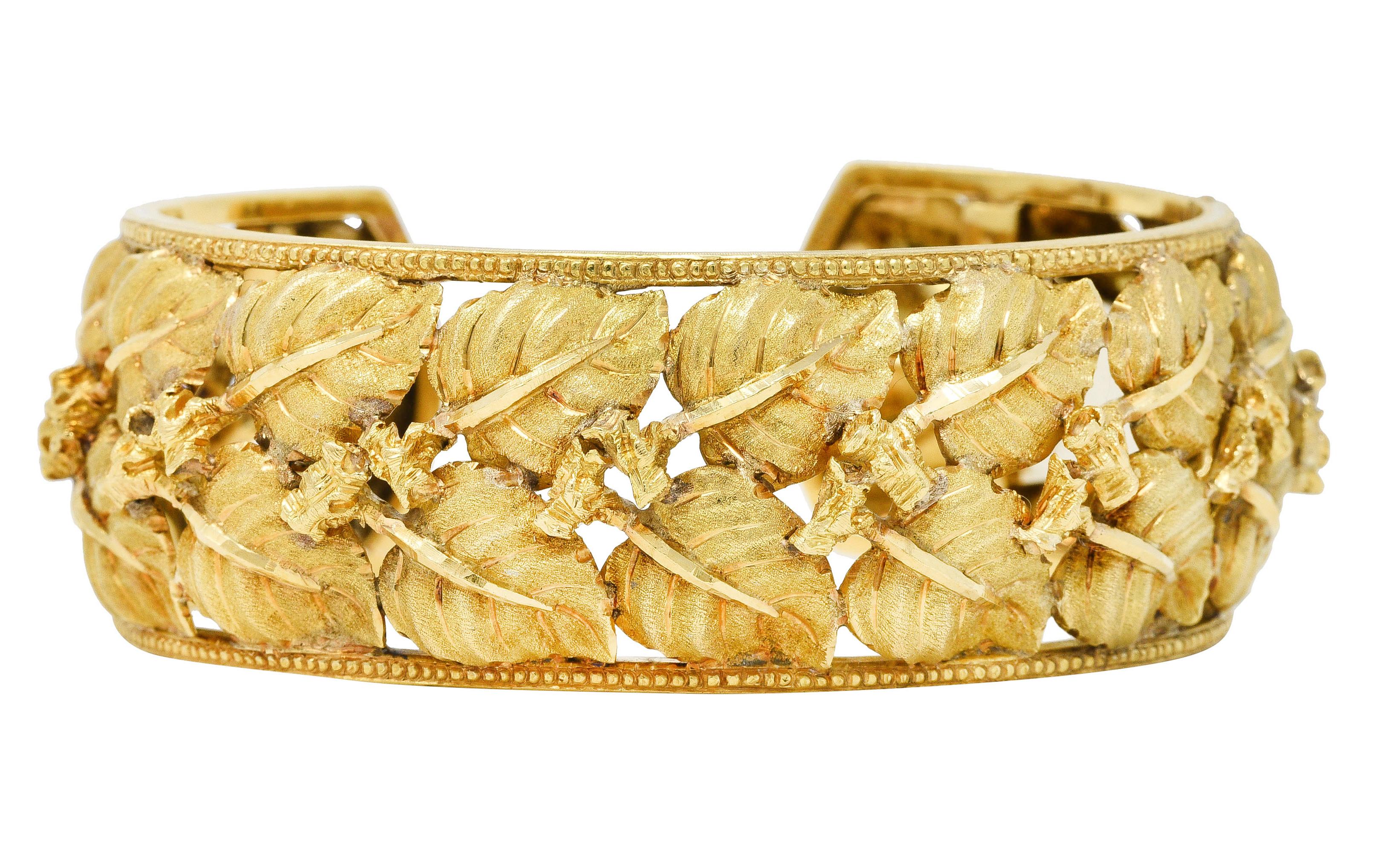 Cuff style bracelet designed with highly stylized birch leaf motif and textured gold 

Centering two rows of textured leaves with high polished veins branching from knotted twig segments

Framed by milgrain edges 

Completed by hinged end

Stamped