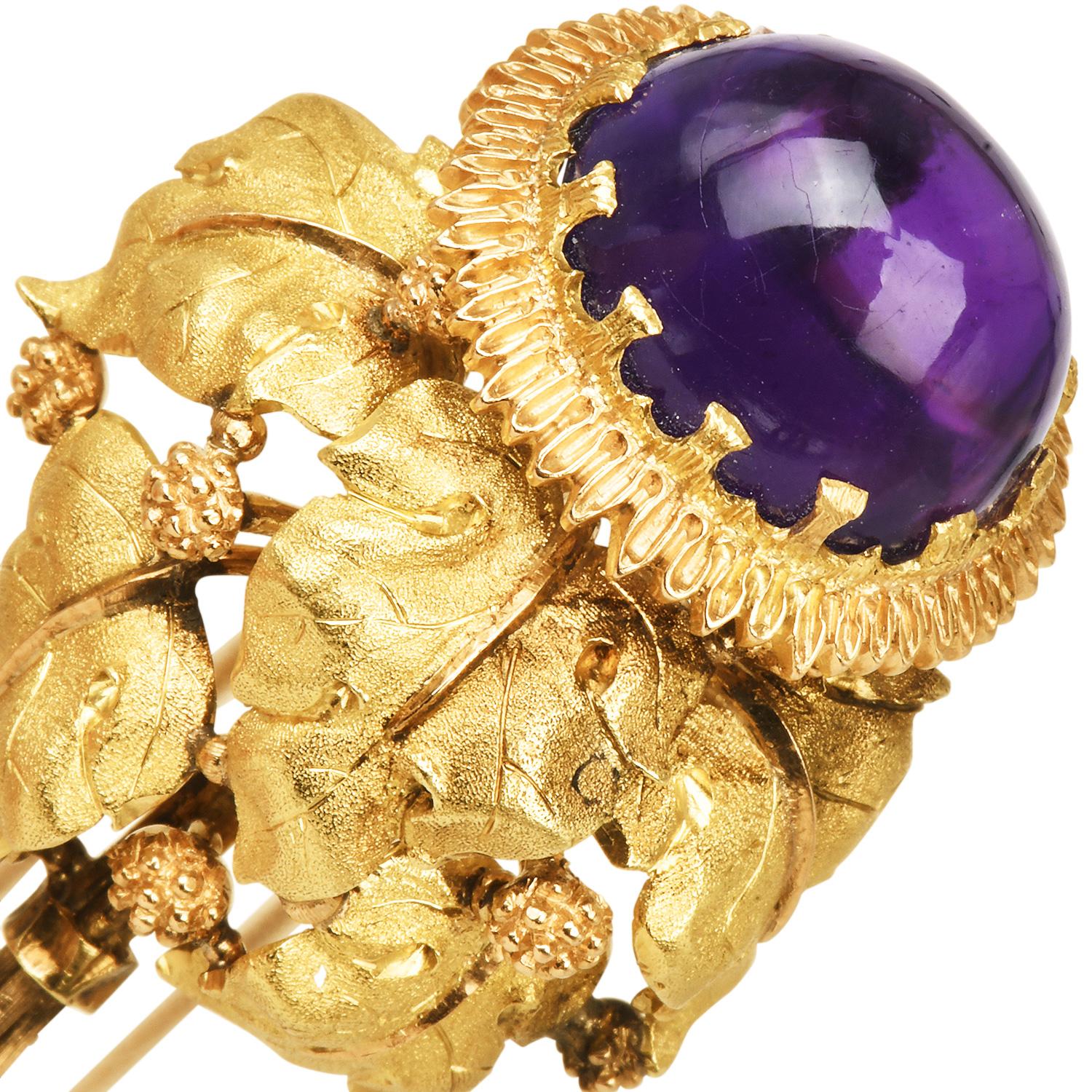 La broche vintage Buccellati Amethyst Acorn en or 18 carats texturé présente une améthyste cabochon richement saturée, sertie au centre d'un motif floral de gland finement détaillé ; la gemme rayonne de teintes violettes royales et d'une douce