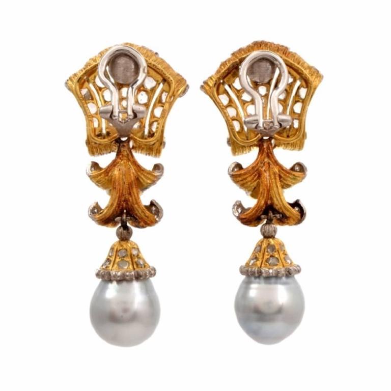 These Vintage Buccellati pendant earrings of unsurpassed aesthetic beauty and classic distinction are crafted in solid 18K yellow gold with white gold clip-backs. These captivating earrings incorporate each a lustrous Baroque silver gray pearl