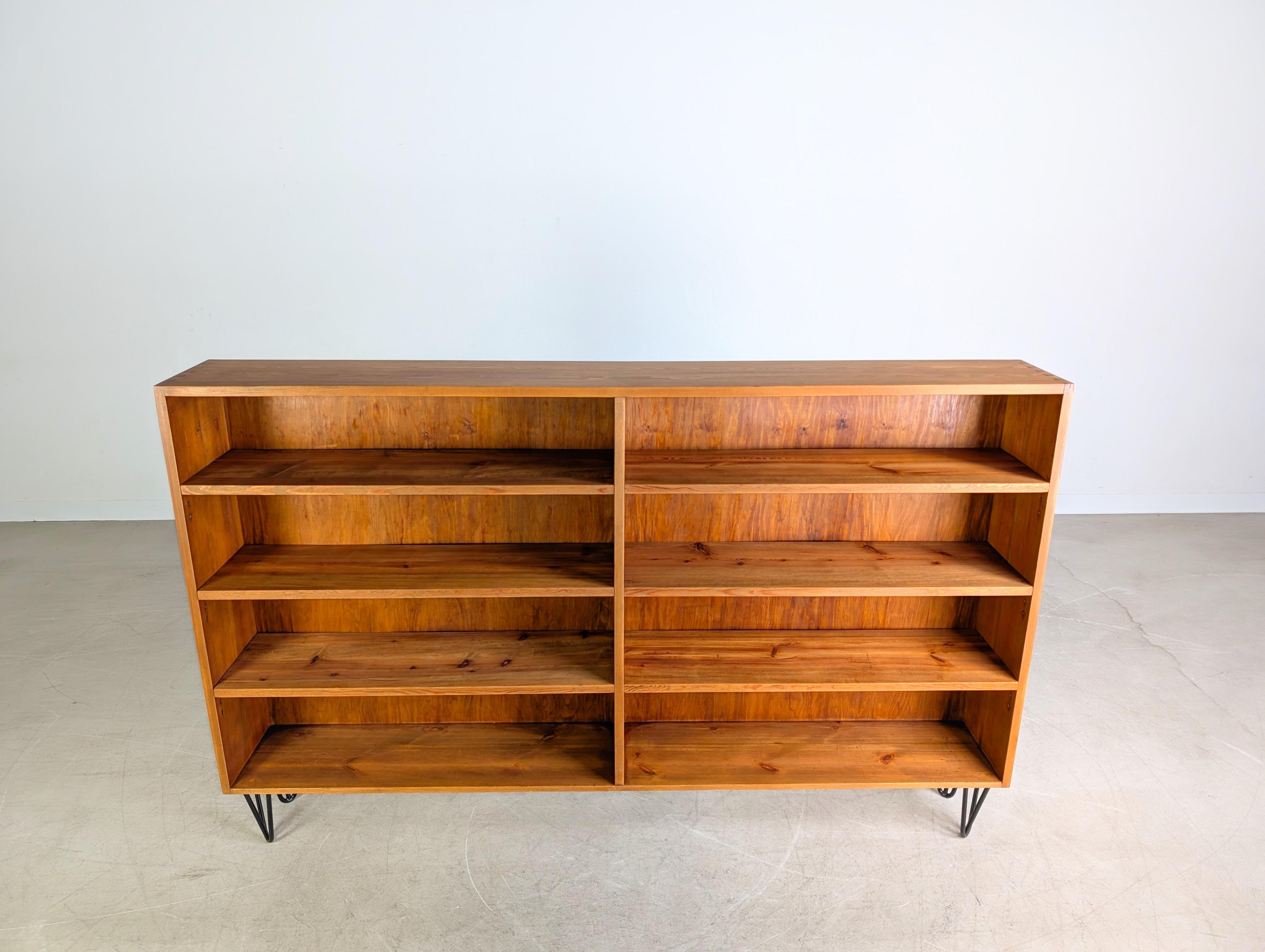 Wir bieten ein wunderschönes Vintage Bücherregal aus robustem Kiefernholz zum Verkauf an. Das Möbel ist aus massiven Holzteilen gefertigt und sehr hochwertig (insbesondere an den Holzverbindungen) verarbeitet. Das Regal steht auf Midcentury