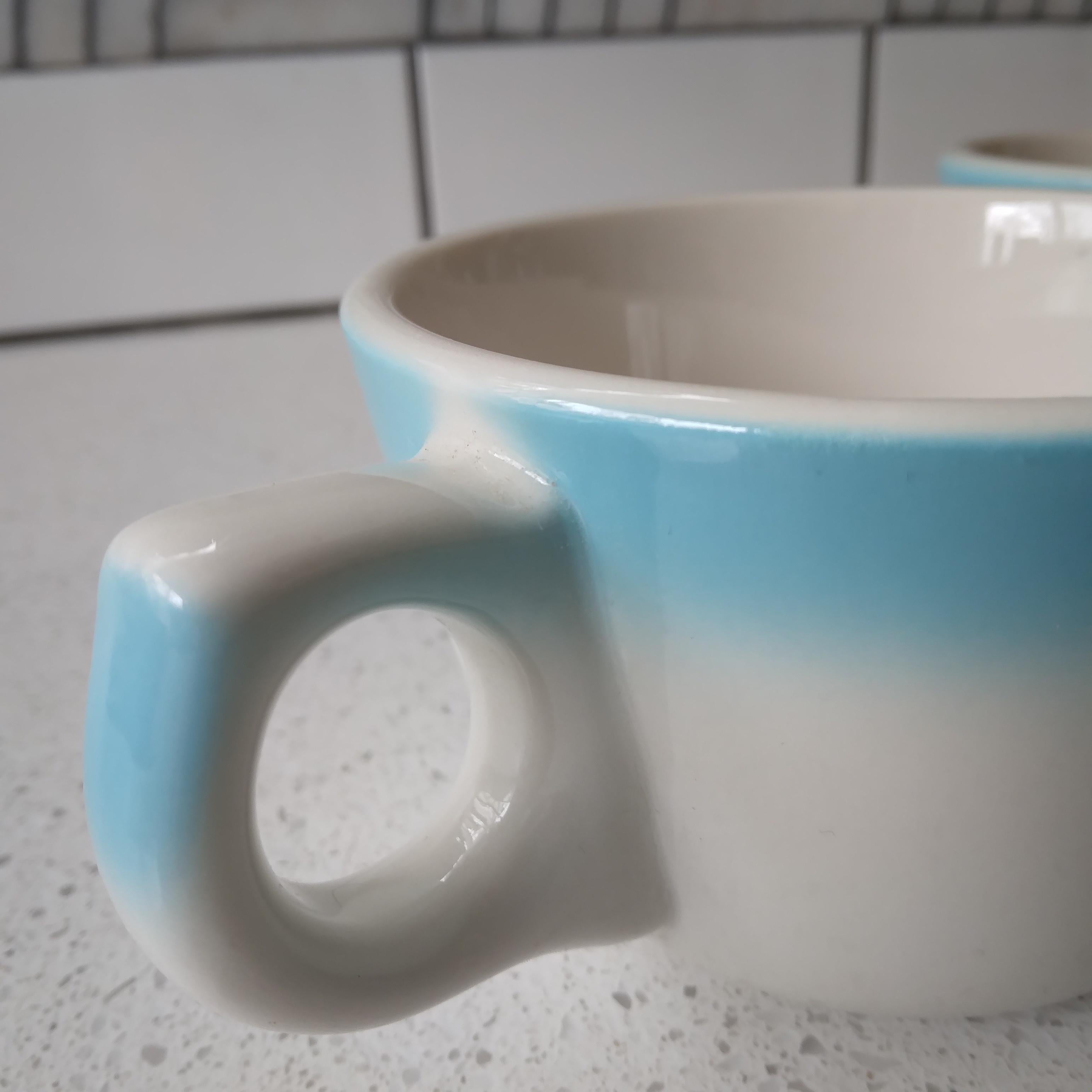 Adorably vintage, these sky blue and off-white tea cups (or small coffee mugs) are a perfect way to add color and history to your collection. Produced in Buffalo, New York, the raised buffalo stamp on the bottom dates the pairbetween 1950-1980. We