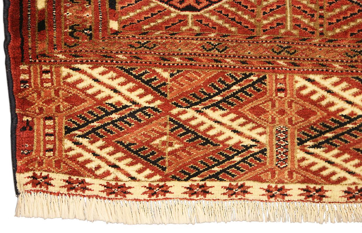 Questo imponente tappeto turkmeno d'epoca, che misura 292 × 220 cm, è uno straordinario esempio di tessitura tribale dell'Asia centrale, ricco di simbolismo culturale e di eccezionale maestria. Il campo è ornato da una ripetizione ordinata di motivi