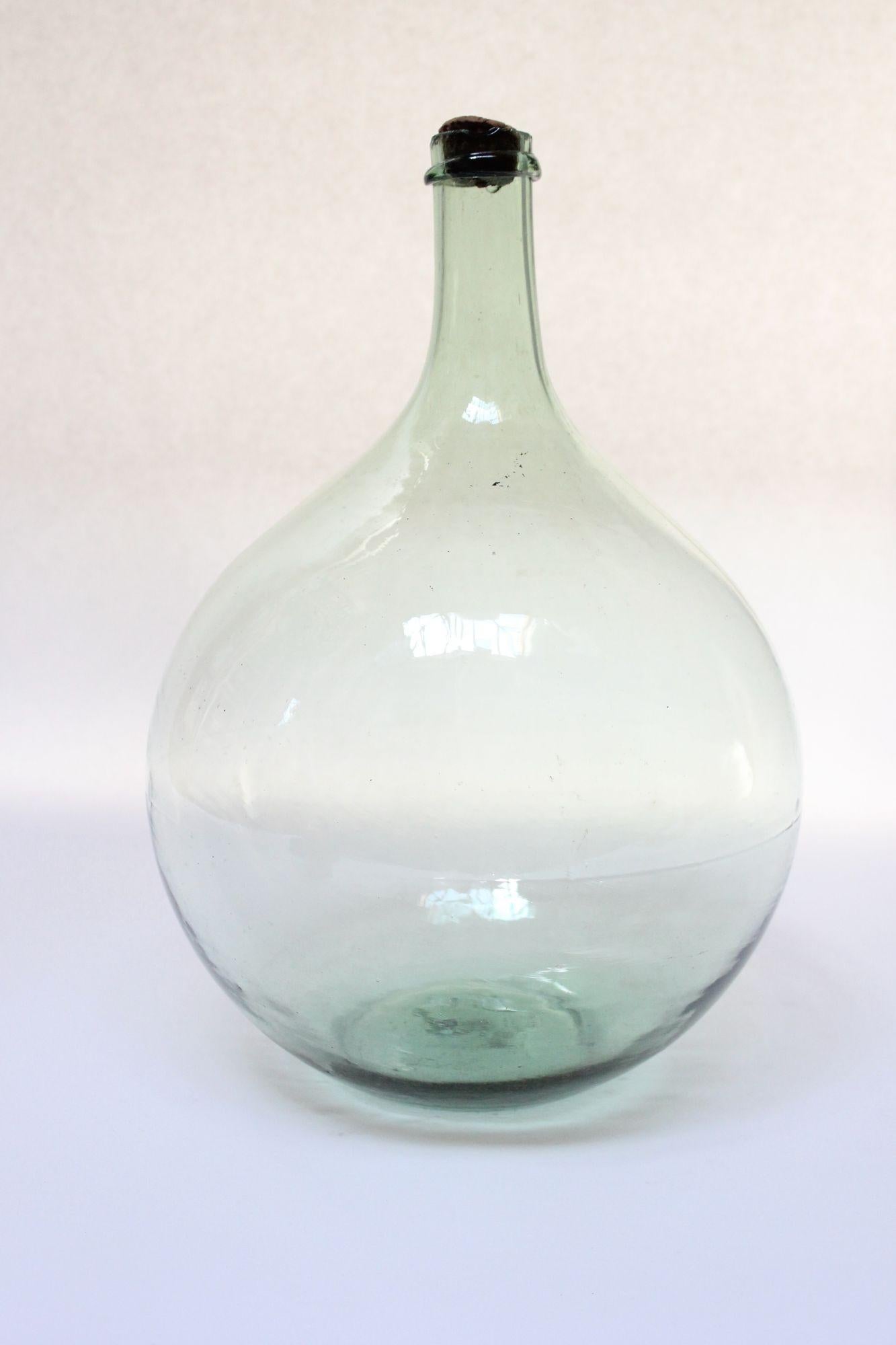 Pale green demijohn/carboy originally used for transporting wine (ca. Early 20th Century, France).
Composed of 'blown-to-mold' glass (a method accepted as 'hand-blowing') exhibiting trapped air bubbles within the glass itself with a sheared lip and