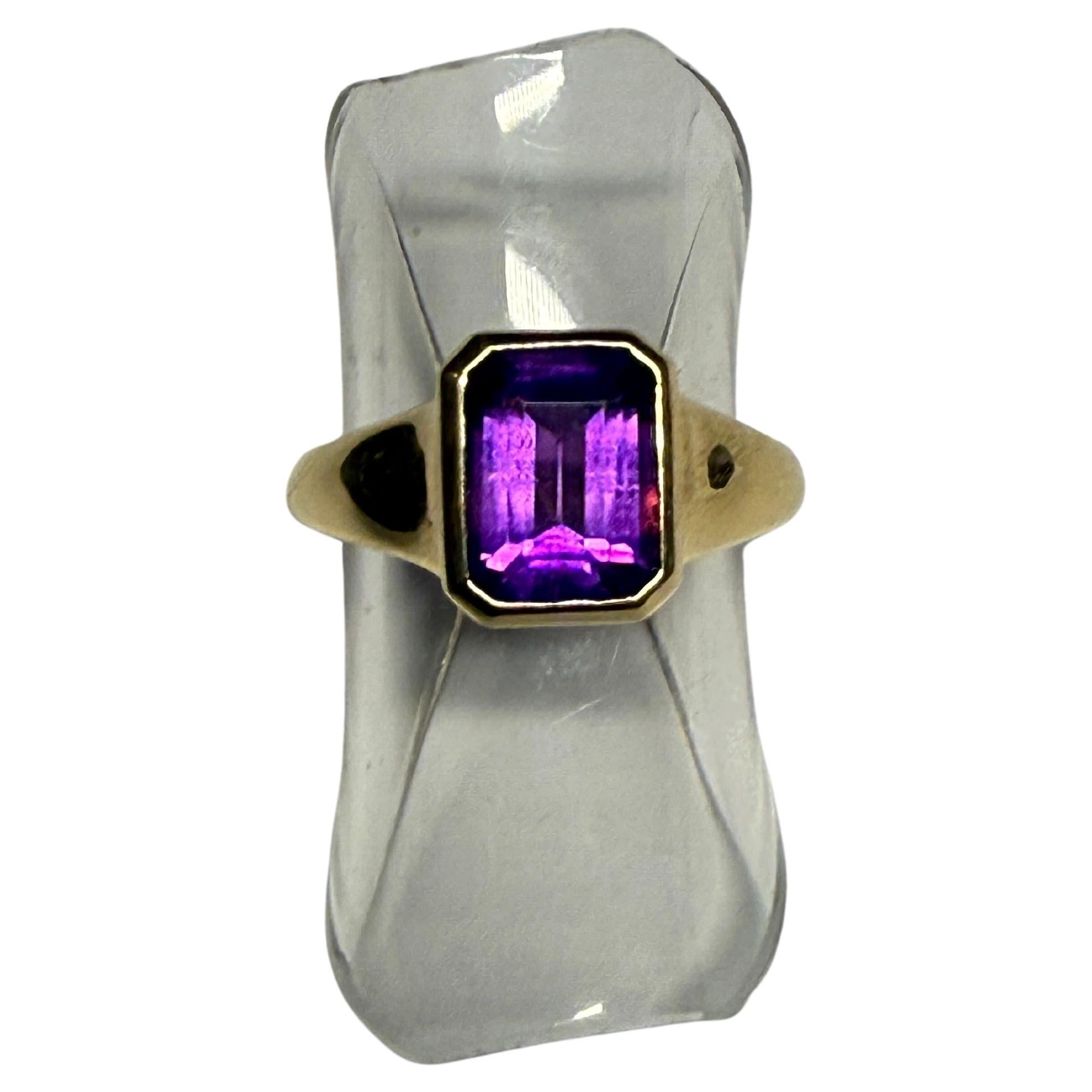 Un audace e giocoso anello Bulgari vintage degli anni '70, realizzato in oro giallo 18 carati e con una vibrante ametista taglio smeraldo incastonata. La gemma presenta toni viola ricchi e saturi e viene fornita con un certificato GRS che ne