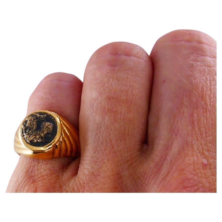 Ein Bulgari-Ring aus 18 Karat Gold mit antiker Münze.
Die Münze ist aus Bronze, griechisch und auf das 5. Jahrhundert v. Chr. datiert. Die Lünette ist in den gerippten Goldschaft eingelassen.
Der Ring gehört zur klassischen Bulgari Monet Collection