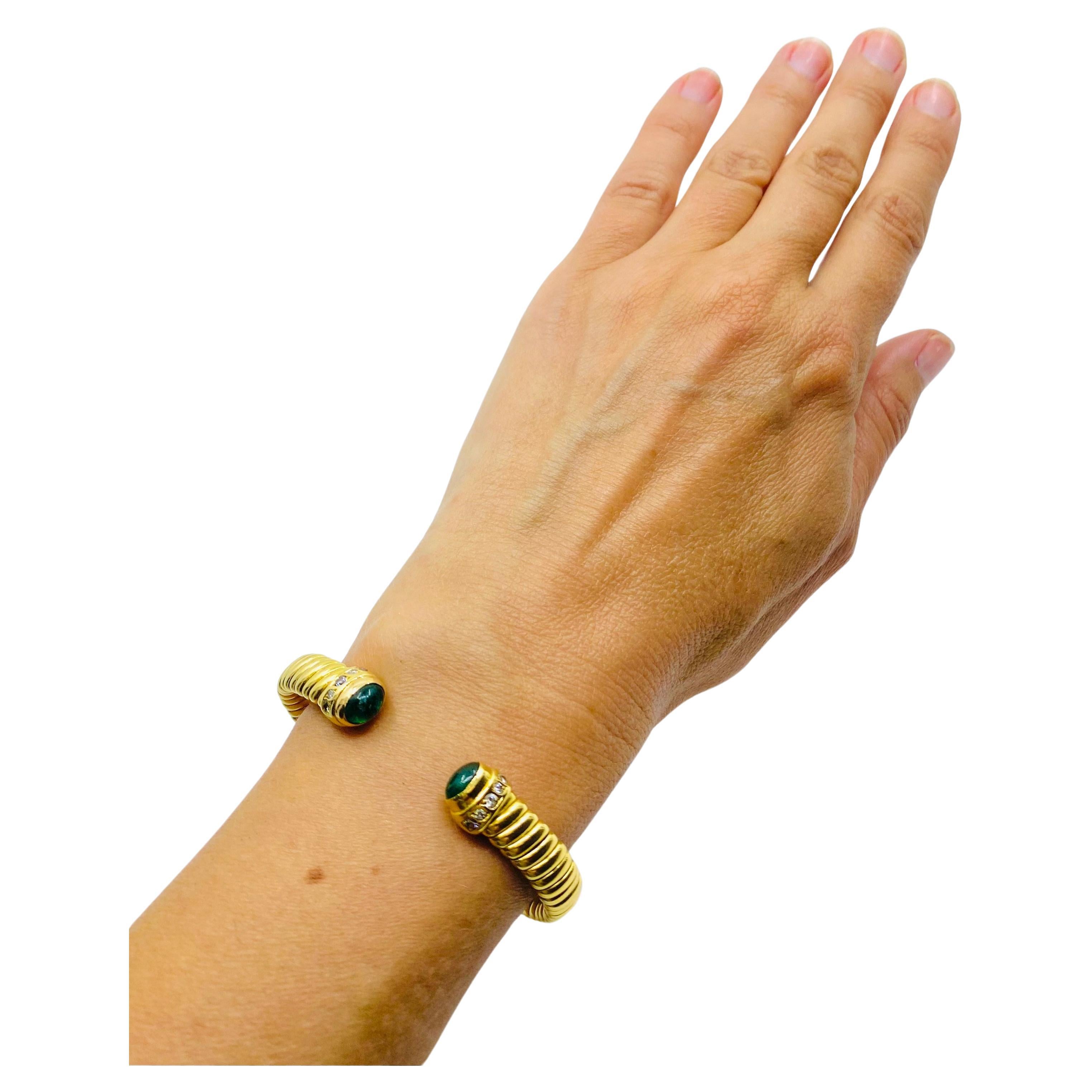 A rare Bulgari tubogas 18k gold bracelet with emeralds. Each tip of this open bangle bracelet is adorned with a gorgeous cabochon emerald. A row of five round cut diamonds are flush set next to the emeralds. This vintage Bulgari bracelet has a rare
