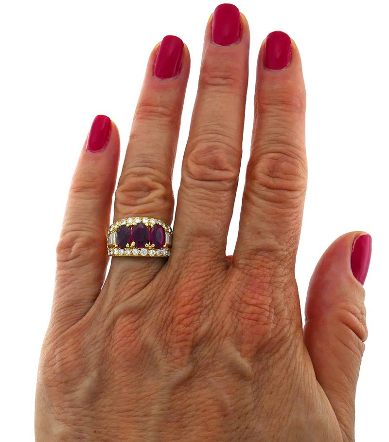 Classy ring featuring three oval faceted rubies (2.64 carats total weight) set in 18 karat yellow gold and accentuated with round brilliant and tapered baguette cut diamonds (G-H color, VS clarity, 1.30 carats total weight). 
Measurements: width