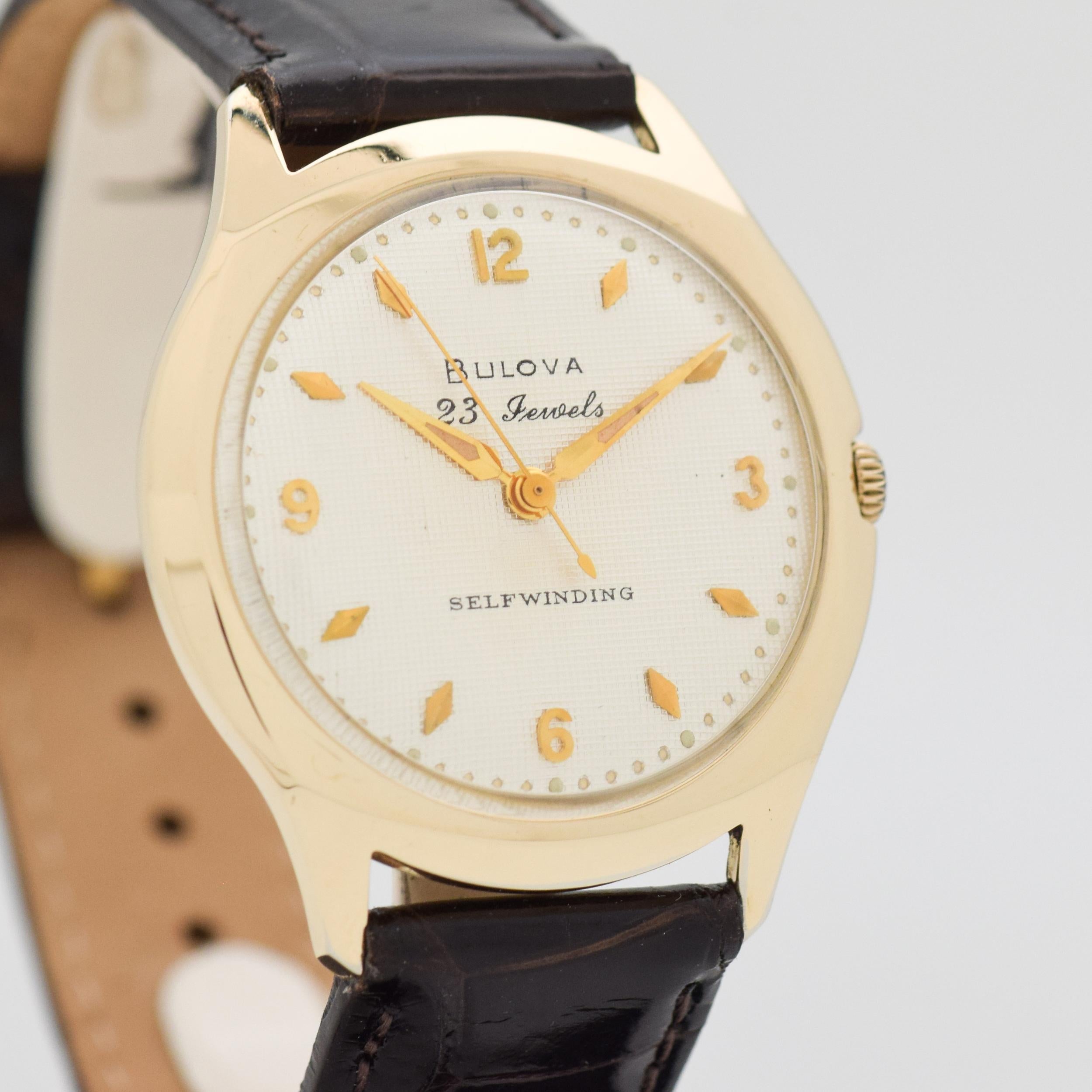 1959 Vintage Bulova 10k Yellow Gold Filled Automatic watch with Original Waffle Textured Silver Dial with Applied Gold Color Arabic 3, 6, 9, and 12 with Beveled Elongate Diamond Shaped Markers. Case size, 34mm wide. 23 jewel, automatic caliber