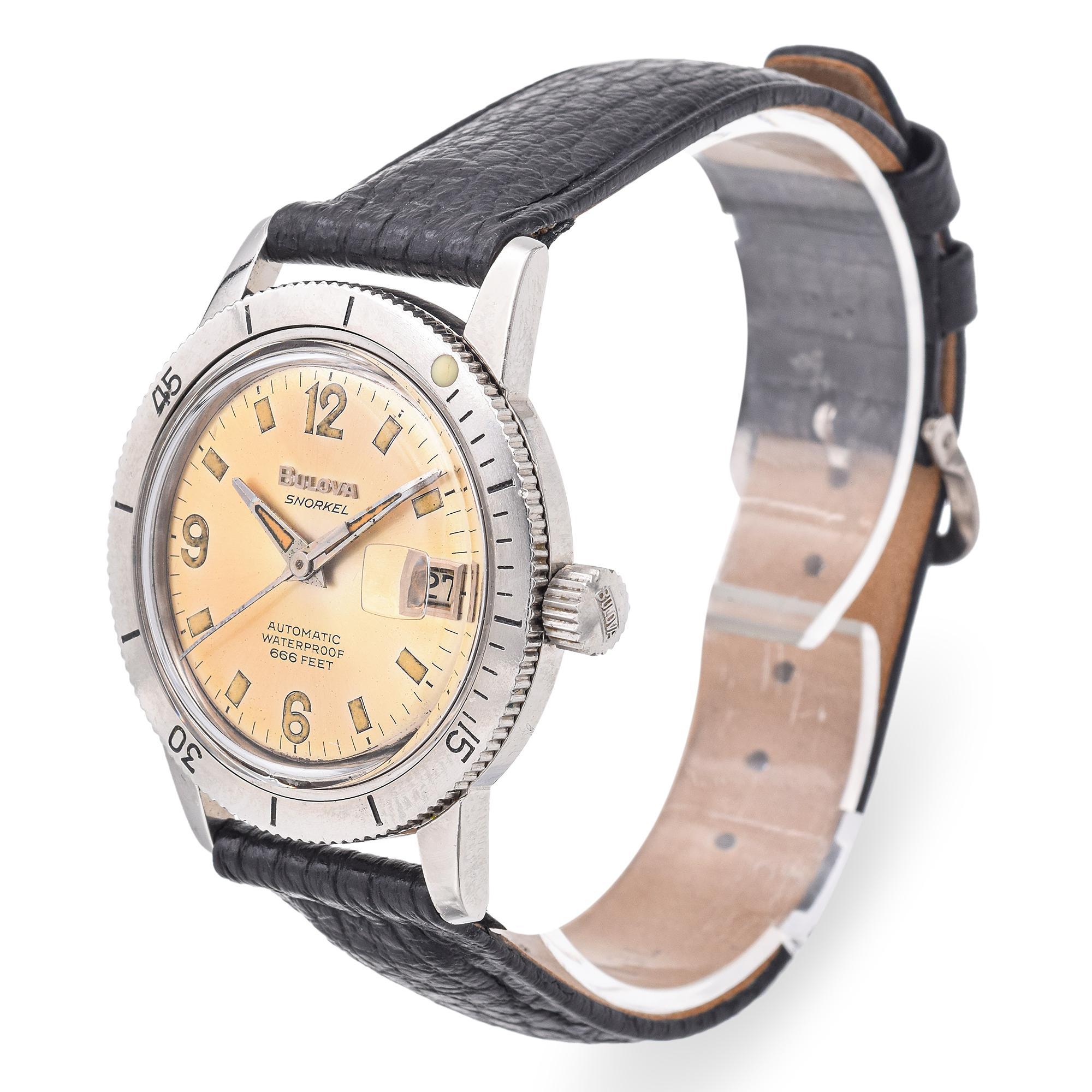 Reloj Bulova Snorkel con esfera color crema con llamativos números arábigos y marcadores luminosos. Ventana de fecha a las 3 horas. Bisel giratorio con marcadores de minutos. Correa de piel negra con acabado texturizado. Movimiento automático.