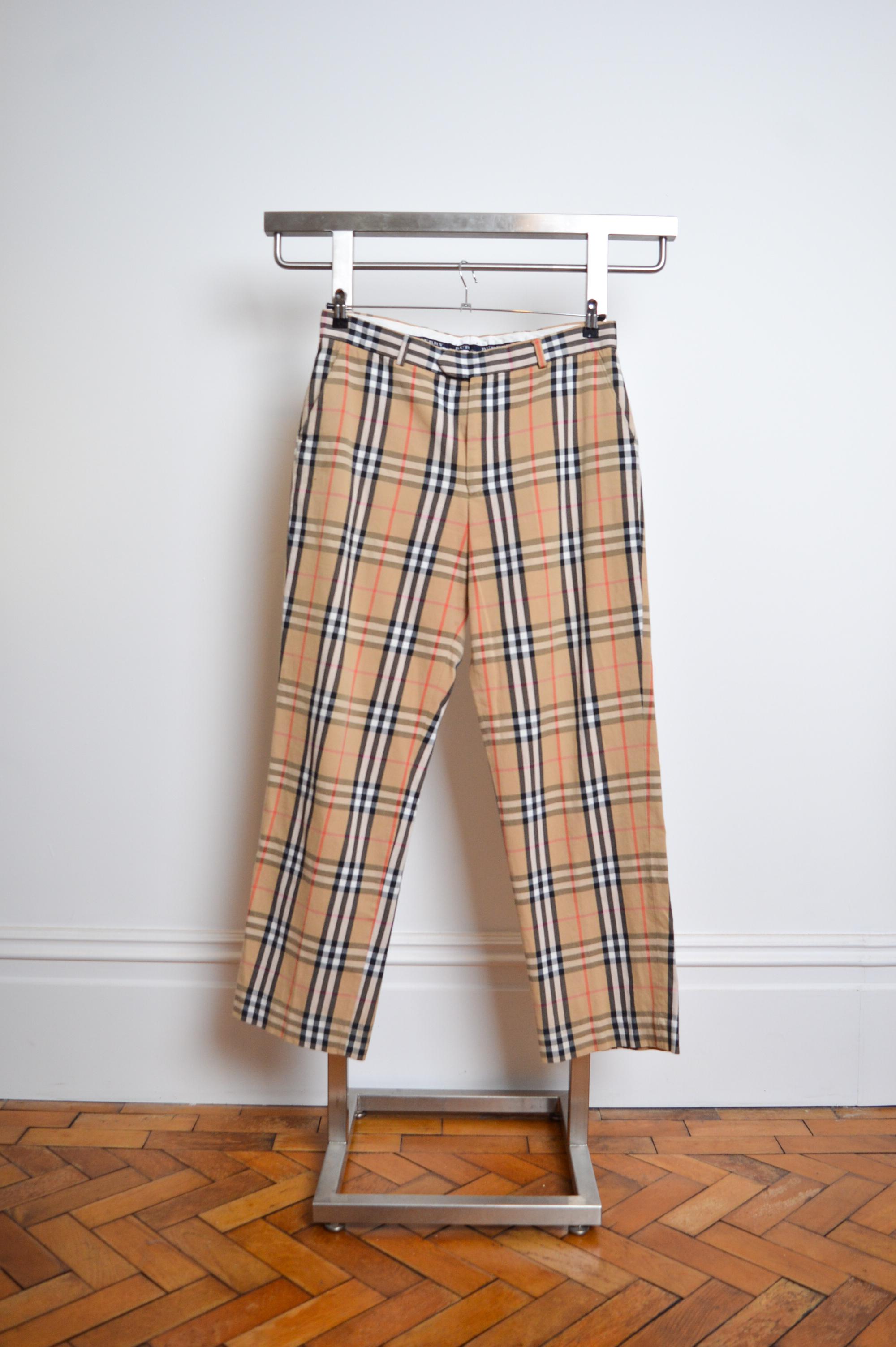 Pantalon à carreaux Vintage 'Burberry' du début des années 2000 dans le motif emblématique Nova. 

Caractéristiques : Fermeture à glissière/bouton, poches, passants pour ceinture, ceinture renforcée avec détails Burberry à l'intérieur. 

98% coton -