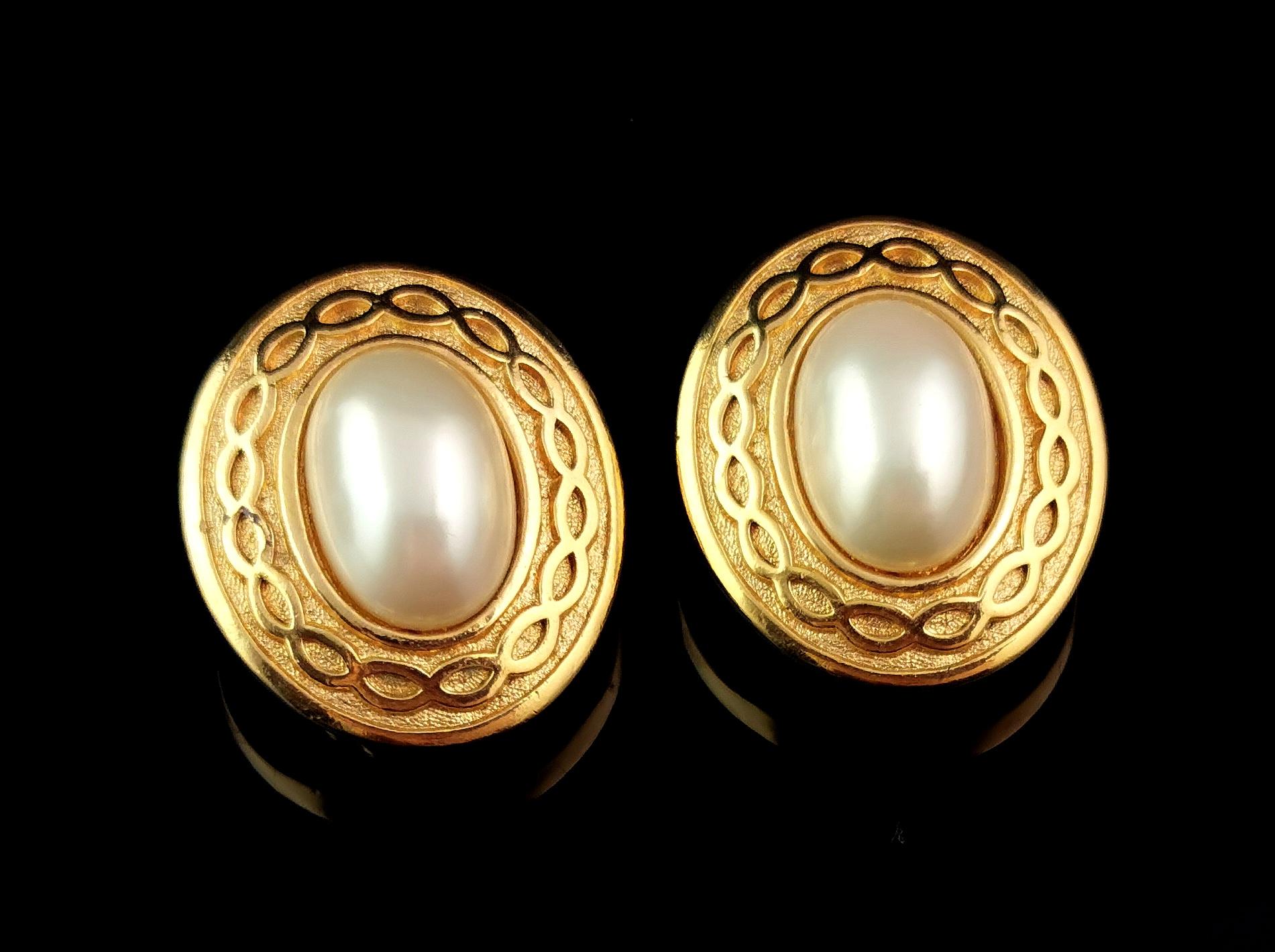 A fantastic pair of vintage Burberry faux pearl clip on earrings.

A medium sized pair of earrings in gold tone, lightly textured metal with a decorative chain link style border.

Each earring is set with a large creamy lustrous faux pearl