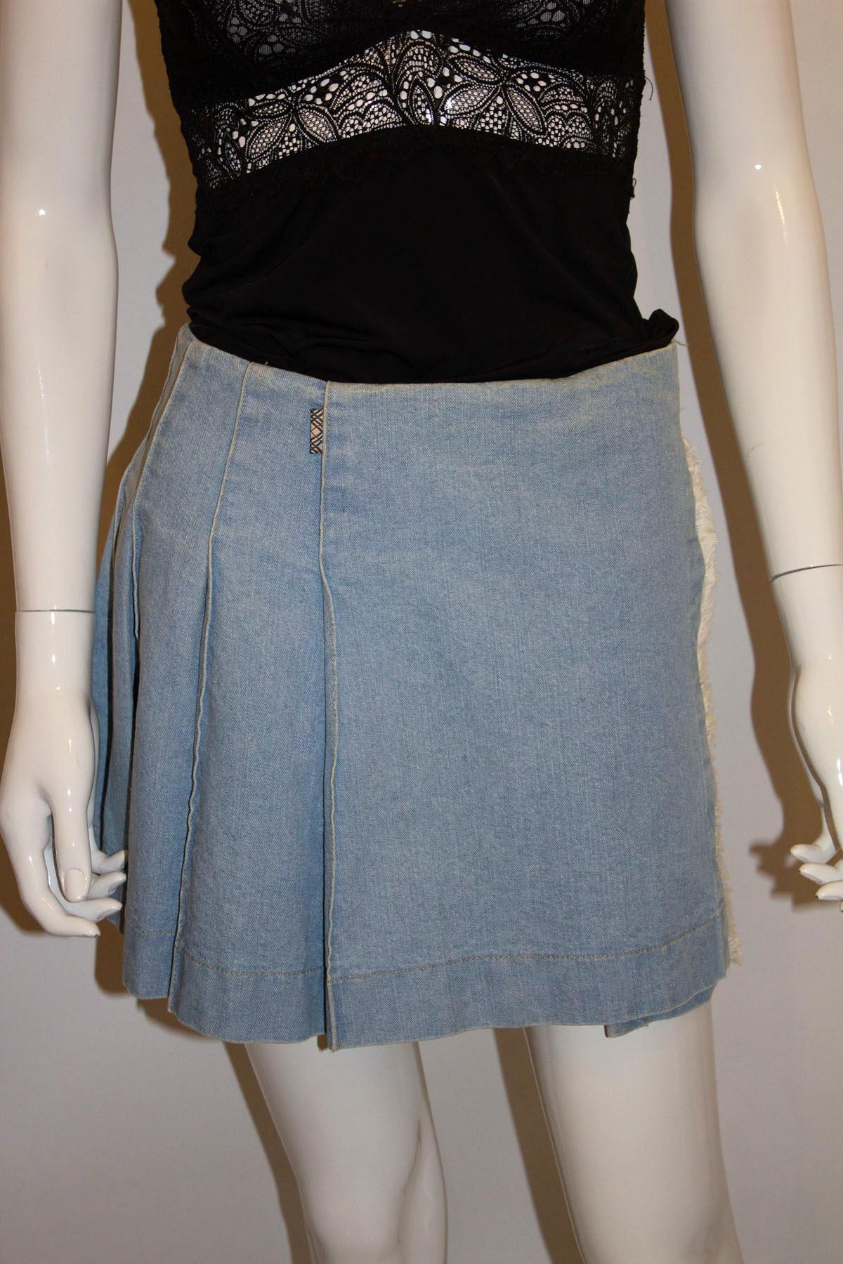 A fun and easy to wear vintage mini kilt by British firm Burberry . In  a heavy denim fabric the kilt has sewn down pleats, producing a smooth line over the hips, and hangs beautifully. It has the Burberry check lining, and a leather strap and