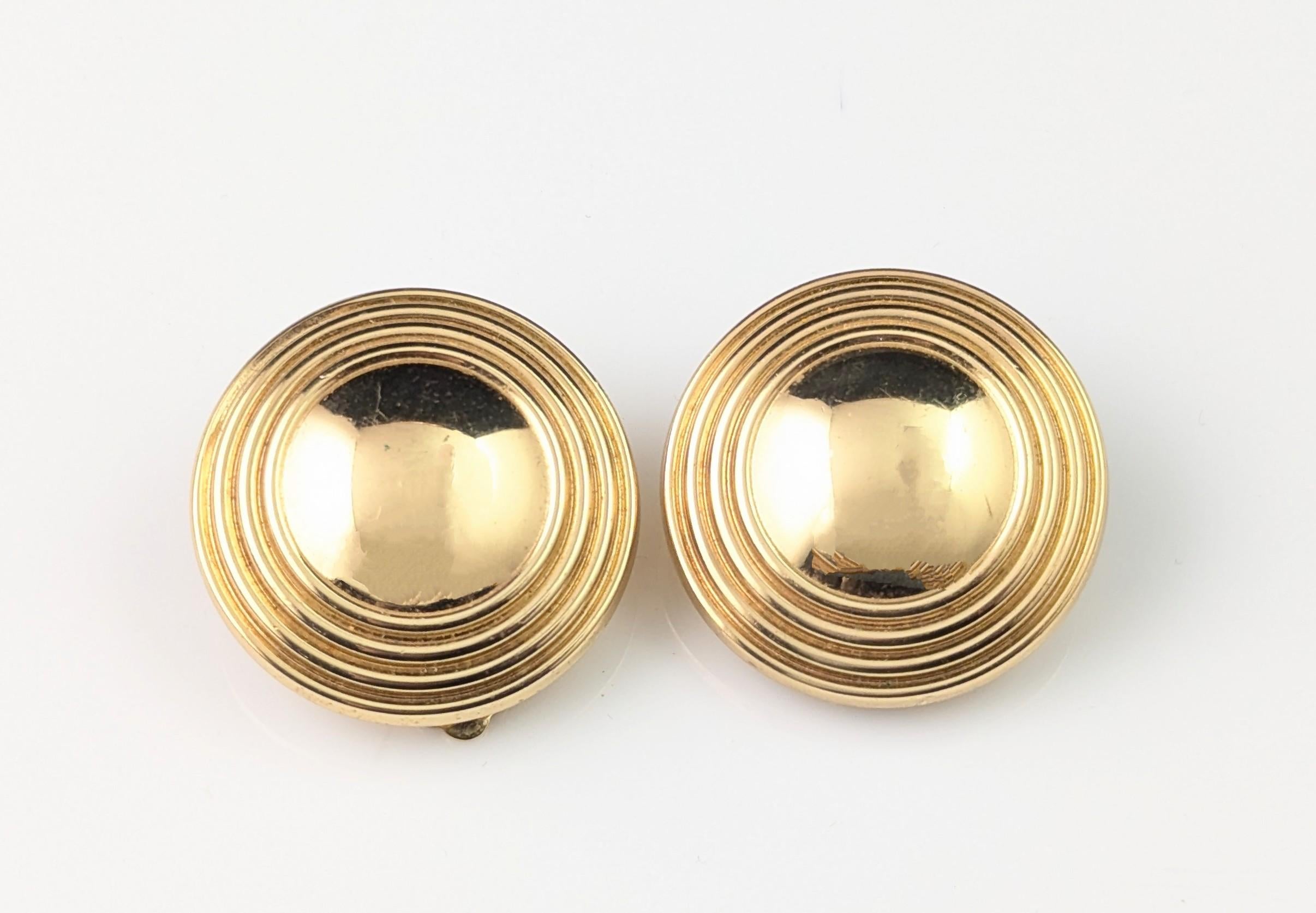 Un fantástico par de pendientes vintage de clip en tono dorado de Burberry.

Un par de pendientes de clip más grandes, tienen forma circular con una cúpula central y un borde de rayas o anillos.

Los pendientes tienen cierre de clip y llevan la