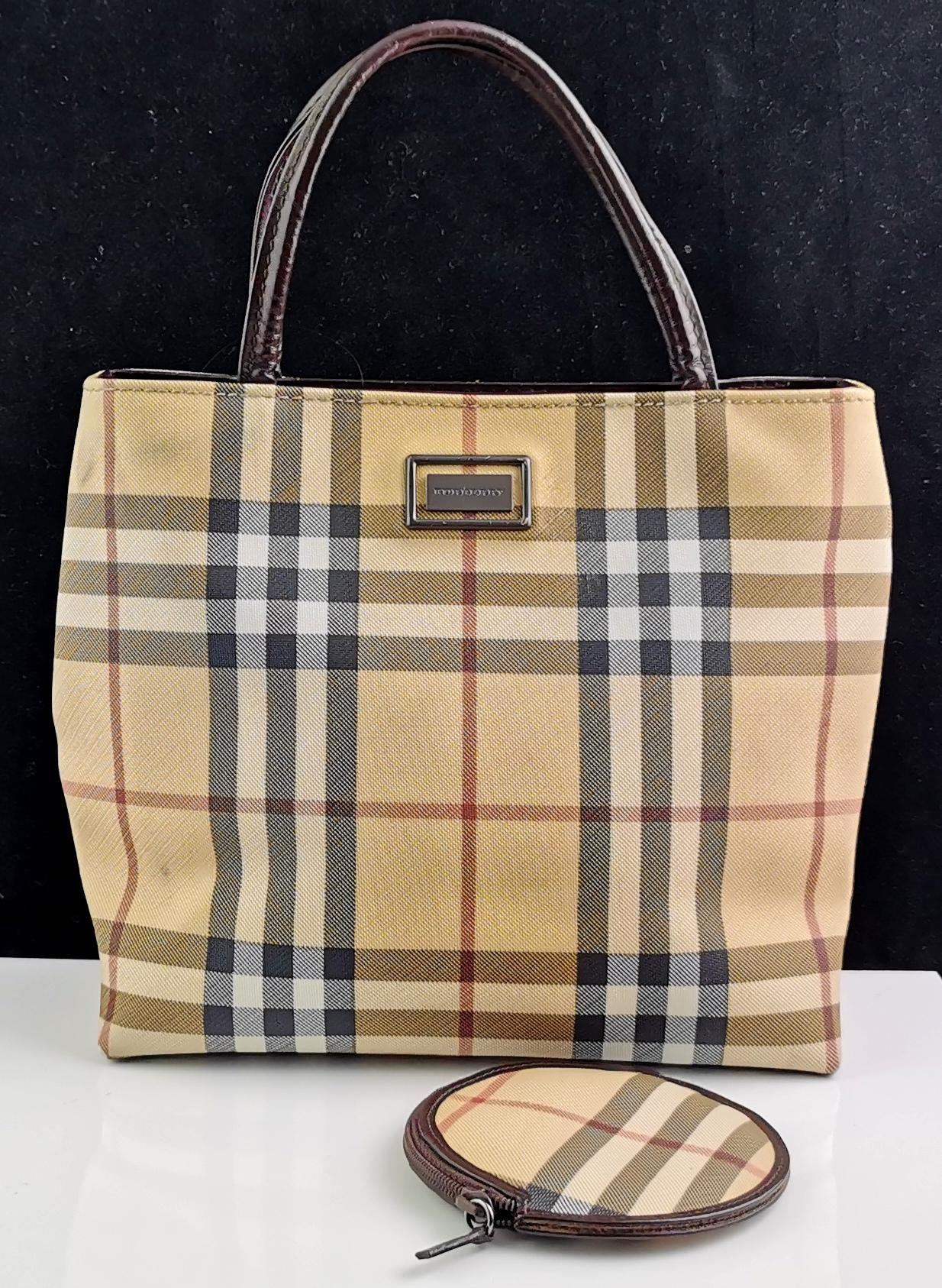 A stylish vintage Burberry mini tote bag with a matching coin purse.

Classic Nova check in a lightly coated canvas.

It has dark brown leather top handles and brown tone metal hardware branded.

Inside the purse there is the Burberry branding on a