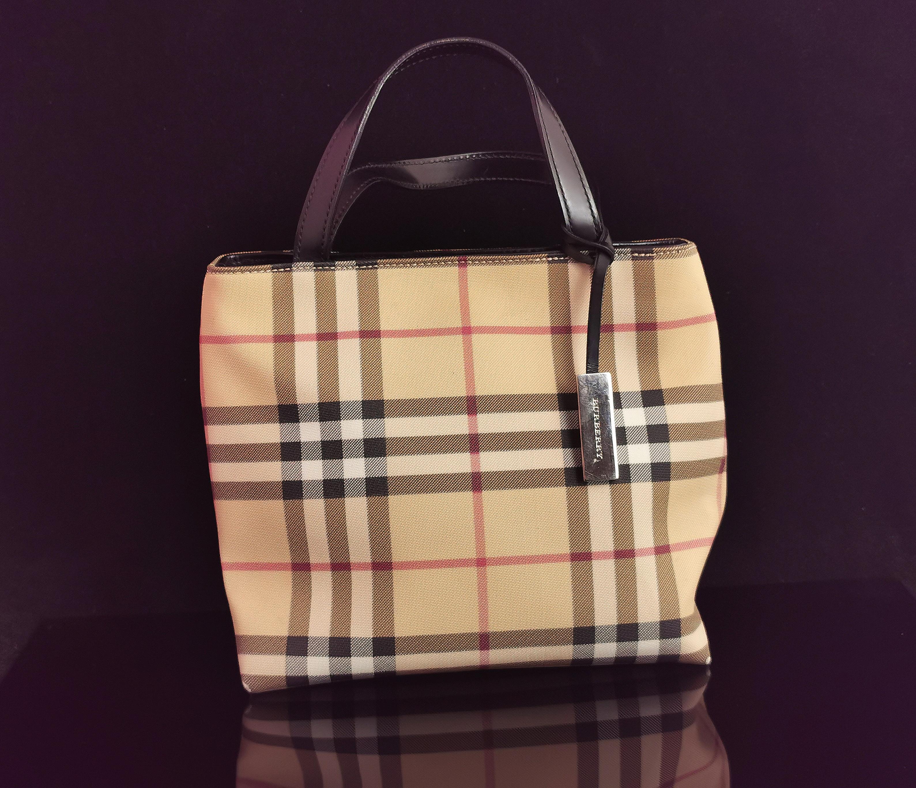 A stylish vintage Burberry mini tote bag.

Classic Nova check in a lightly coated canvas.

It has a black leather handle and silver tone hardware branded.

Inside the purse there is the Burberry branding on a leather tag, a small zipped compartment