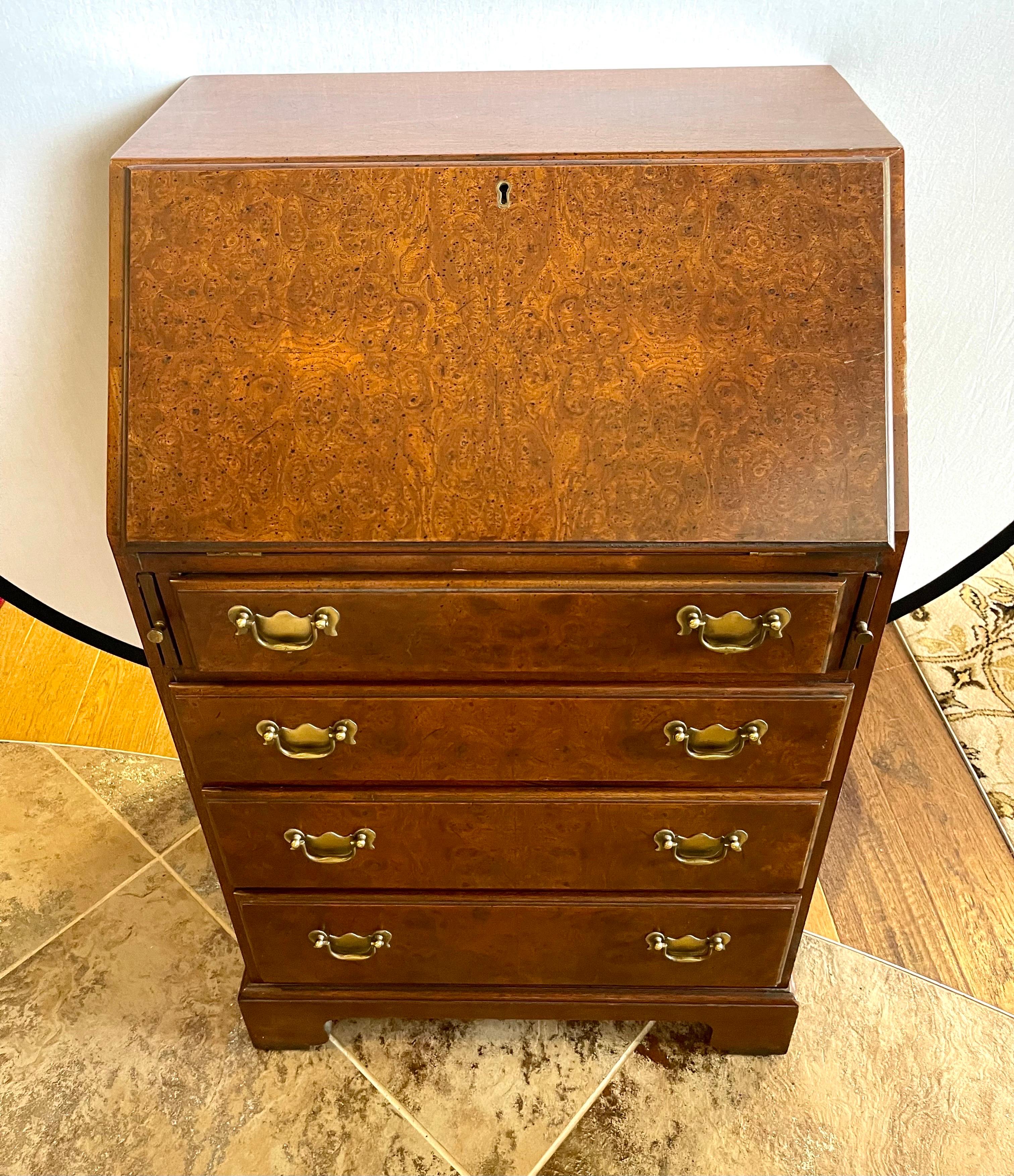 Elegant and small in size, a traditional burl walnut secretary desk. Features a drop down writing surface and multiple drawers and cubbies. Bottom portion has four dovetailed drawers with brass pulls. Perfect for a smaller space.