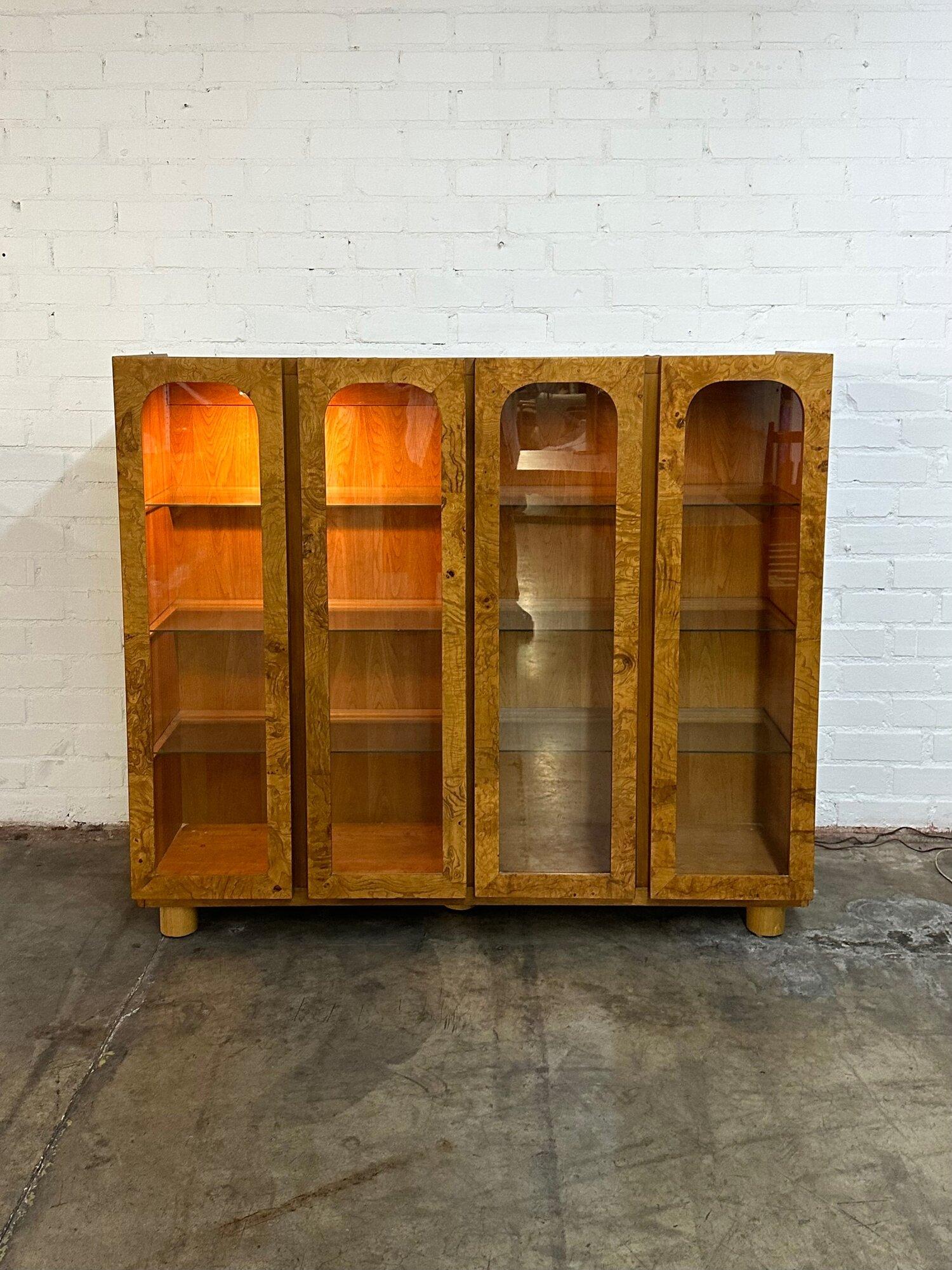 W64 D17 H56

Bookcases in good vintage condition. Item features nice curved center glass doors, well preserved Burl wood veneer , and rounded solid oak cylinder legs. The lights inside are fully functional but the right side bulb is fading and