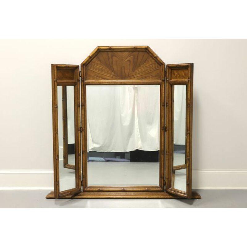 An Asian style tri-fold dresser mirror by Burlington House. Pecan, burlwood & styled faux bamboo frame with an unusual trapezoid shape to the top. Features bevel edge mirrored glass in the center and two side mirrors that can fold inward. Designed