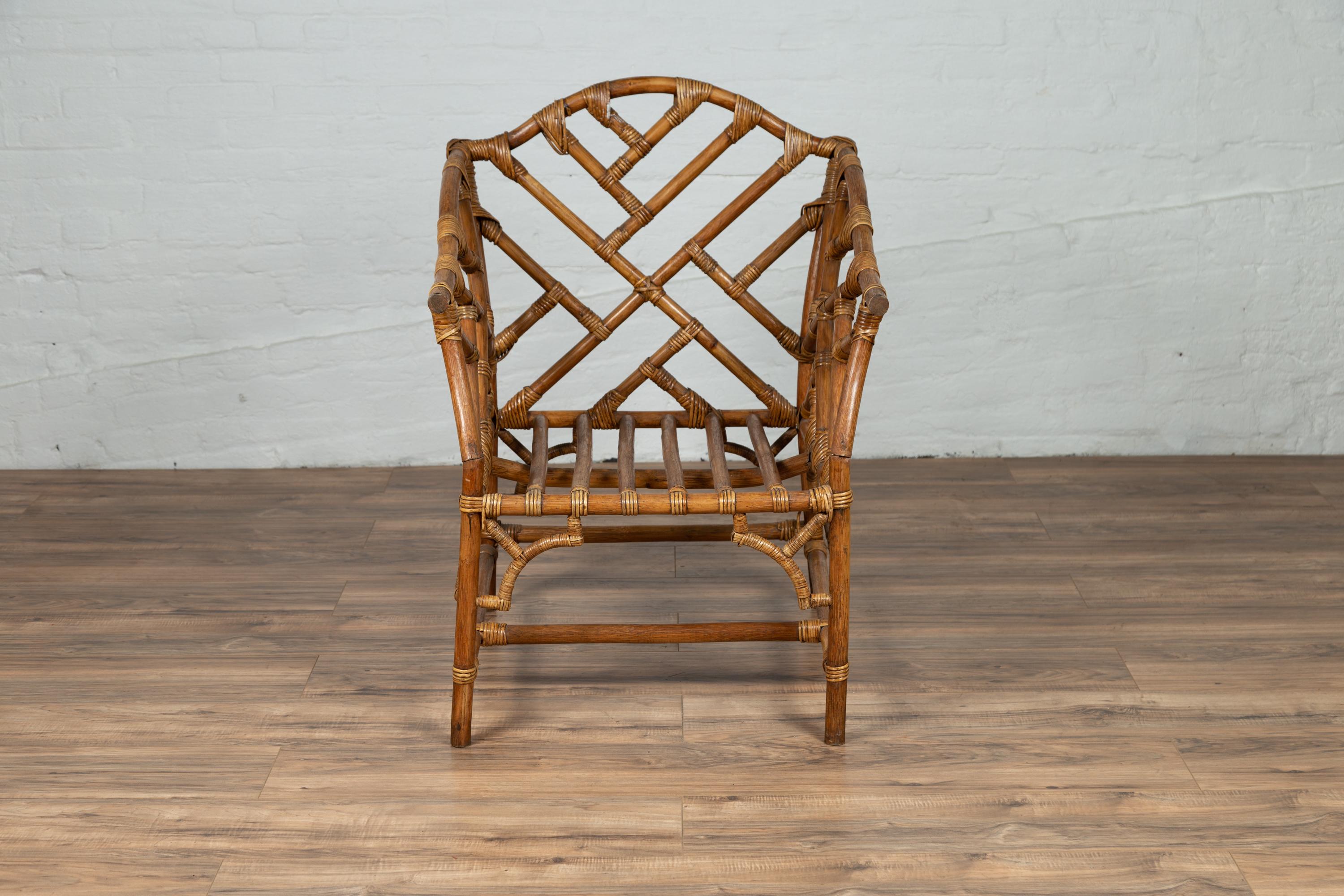 A vintage Burmese rattan and bamboo armchair from the mid-20th century with Chinese Chippendale style patterns. Found in Burma, this stylish rattan and bamboo armchair features an intricate pattern that inspired the Chinese Chippendale style. The