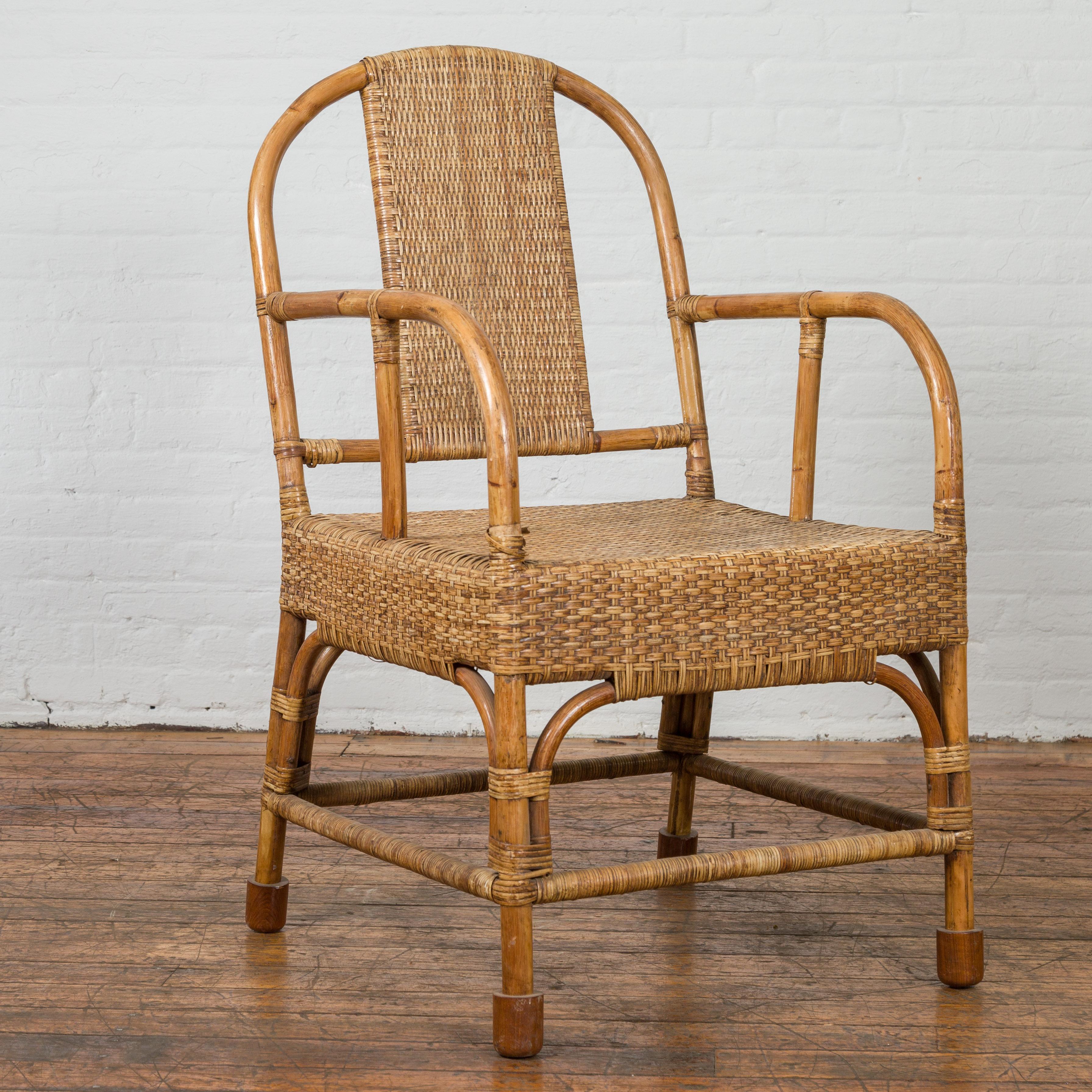 A vintage Burmese country style hand woven rattan armchair from the mid-20th century, with rounded open back, looping arms and side stretchers. We currently have several chairs available, priced and sold individually. Created in Burma during the