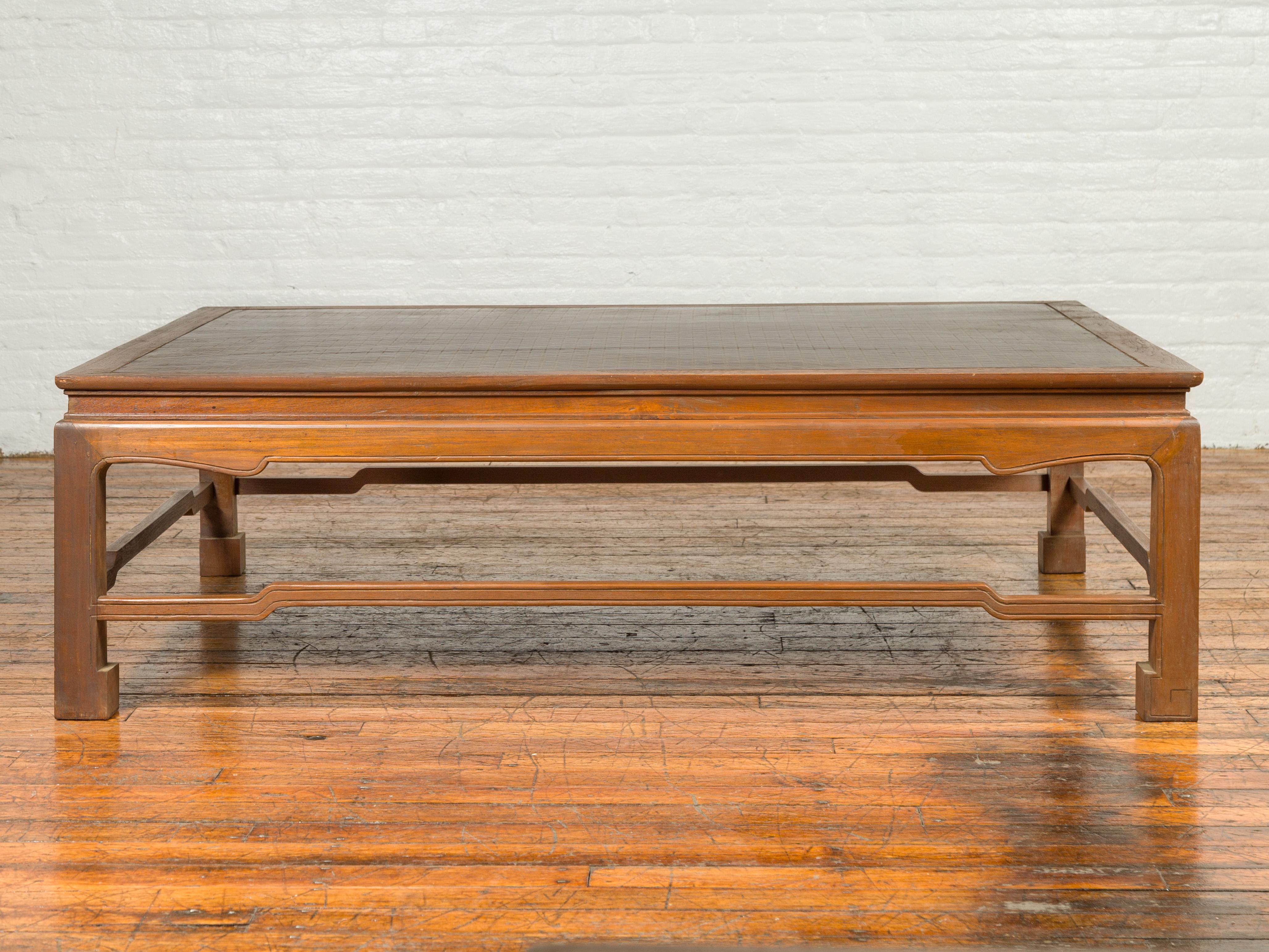 A vintage Burmese coffee table from the mid-20th century with negora lacquer top, humpbacked stretchers and scrolling feet. Crafted in Burma during the mid-20th century, this coffee table features a rectangular negora lacquer top with central board,