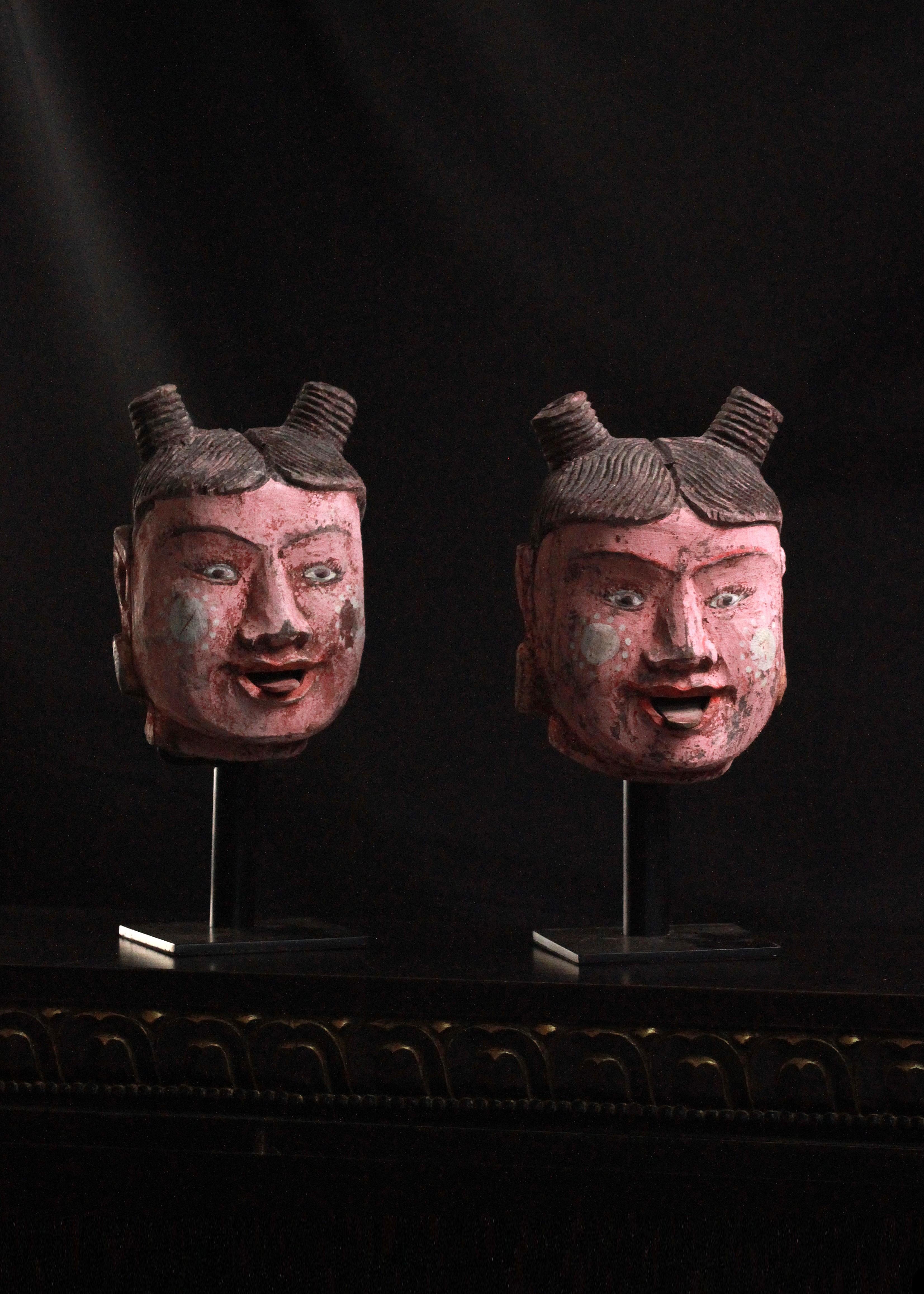 Cet ensemble captivant de deux têtes de marionnettes polychromes, méticuleusement montées, transporte les spectateurs dans le monde vibrant de l'art birman. Fabriquées à la main, ces têtes de marionnettes expressives sont pleines de caractère. Leurs