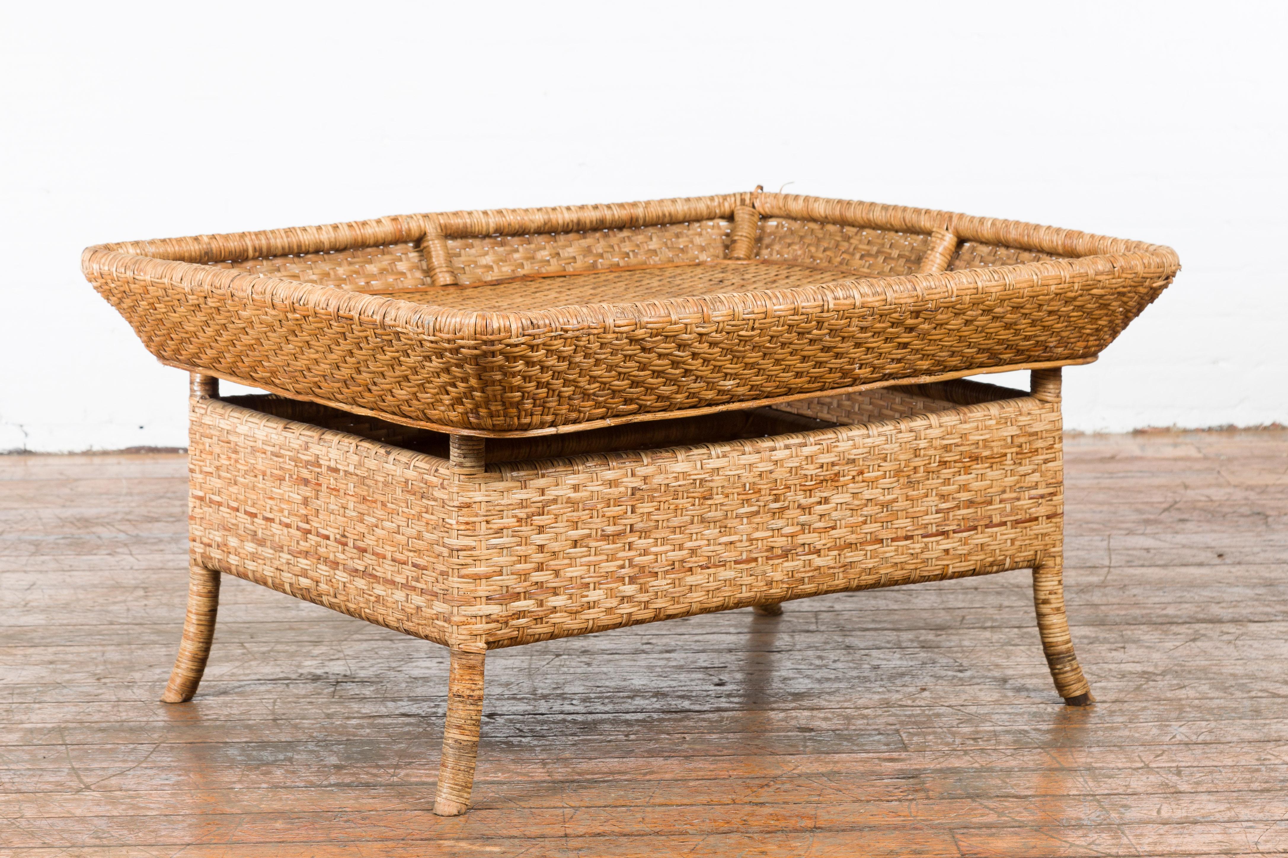A Burmese rattan and bamboo vintage coffee table from the mid 20th century with a spacious squared open tray top. Created in Burma during the mid century, our vintage coffee table features a beautiful display of rattan and bamboo artistry that adds
