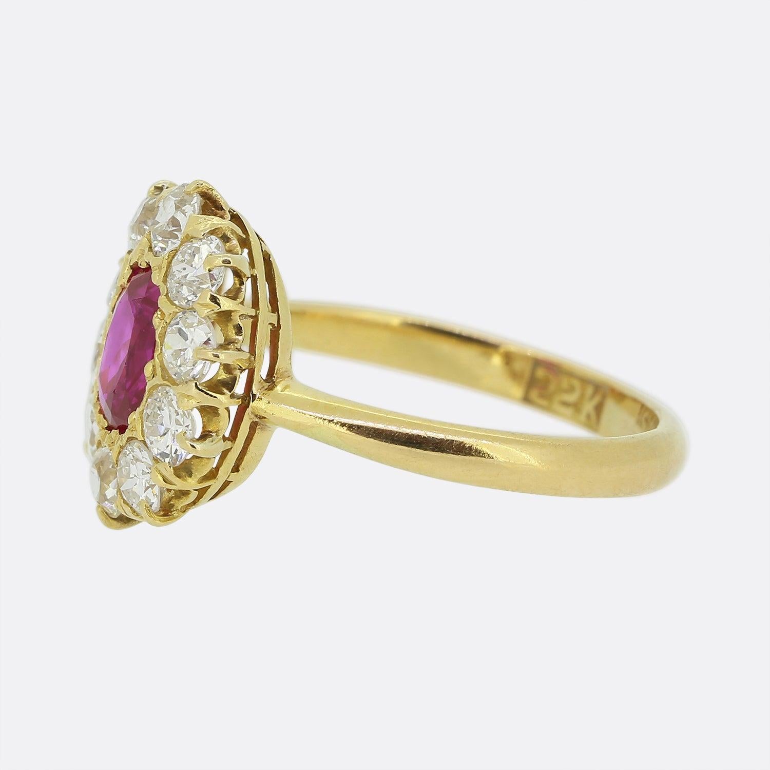 Here we have a fabulous ruby and diamond cluster ring. This vintage piece showcases a single oval shaped natural Burmese ruby at the centre which possesses a vivid red colour with a slight pinky undertone. This vibrant principle stone is then