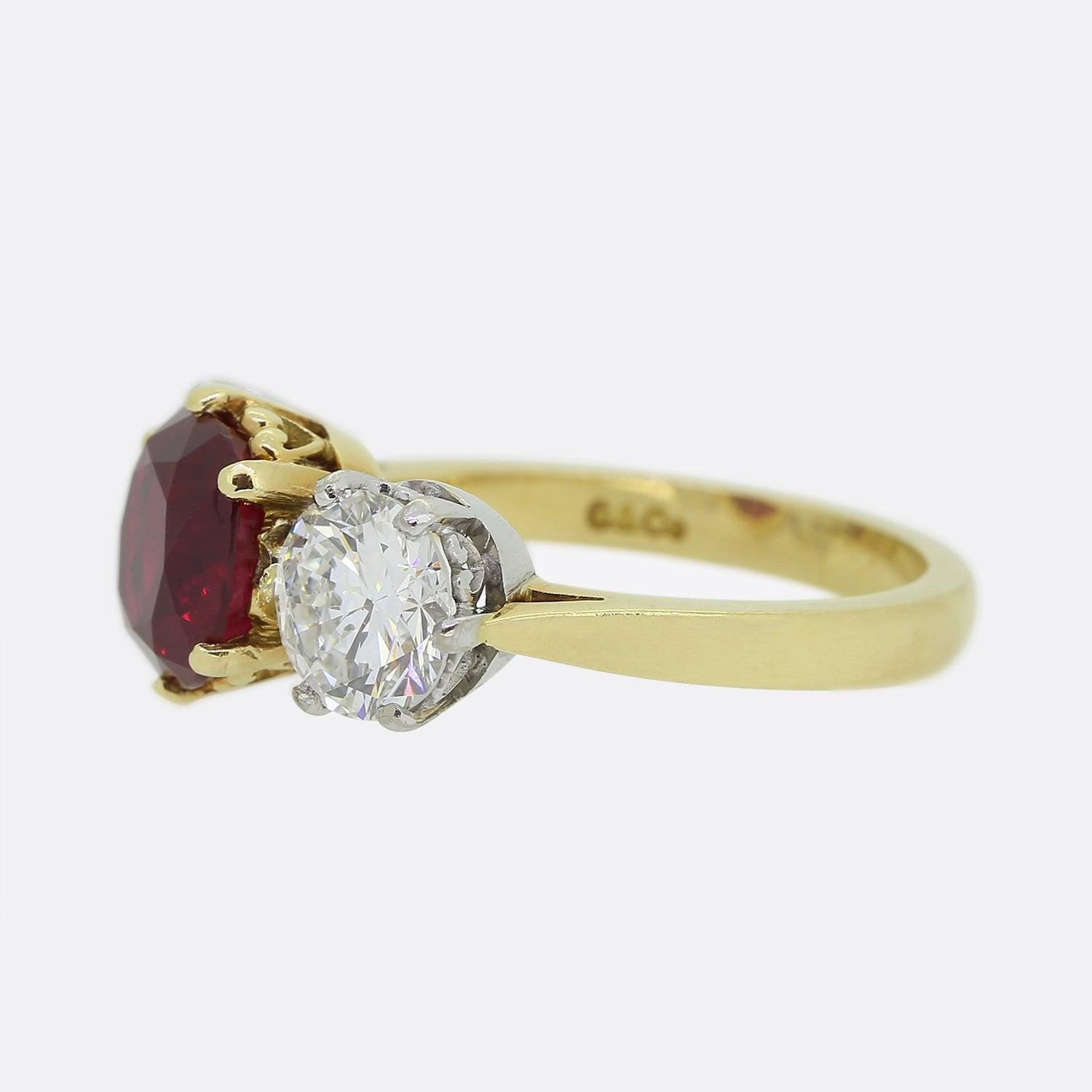 Here we have a truly breath taking ruby and diamond three-stone ring. The focal point of this piece being the 3.08ct antique cushion cut Burmese ruby which sits proud in a six clawed setting at the centre of the face. This principle stone has been