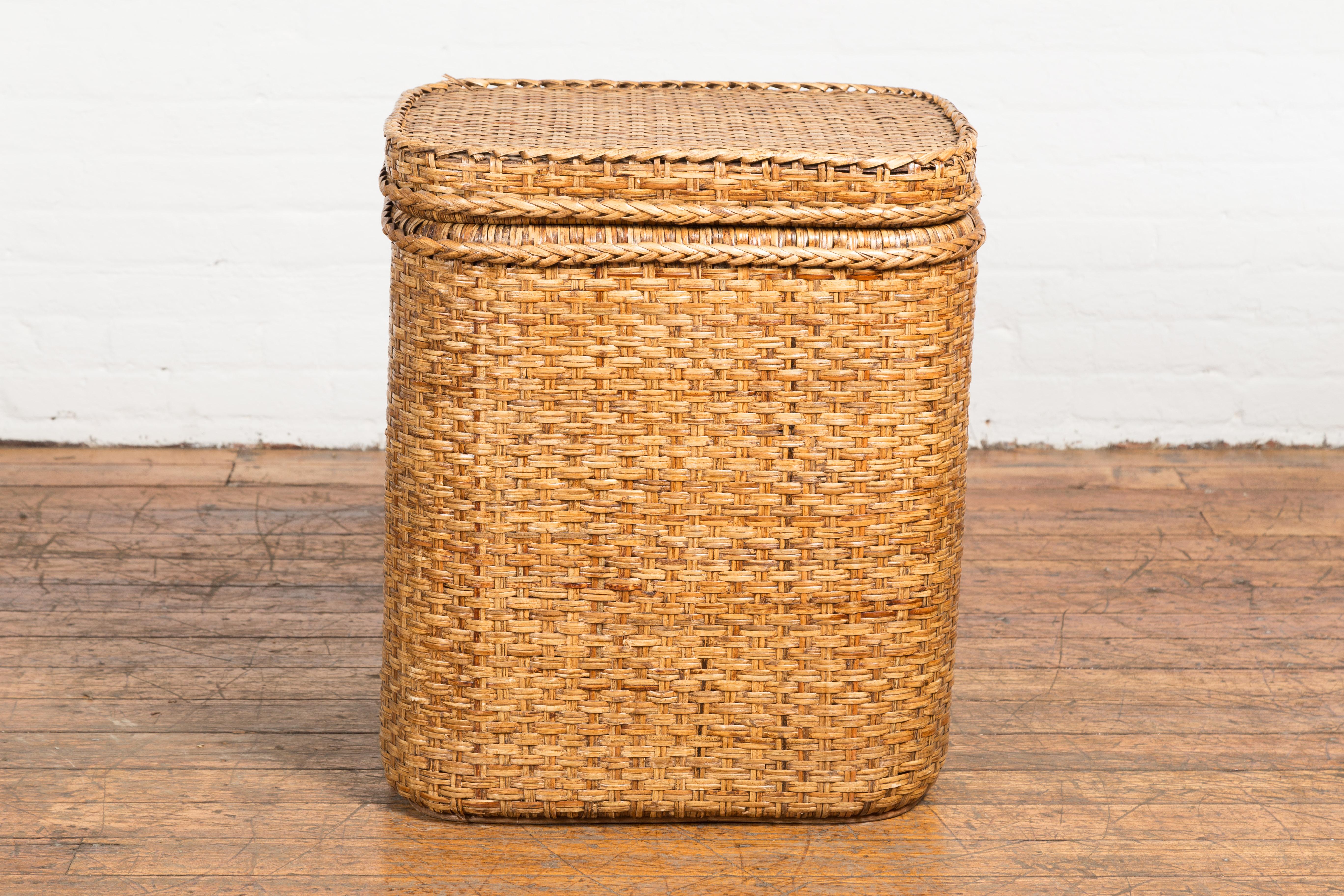 A vintage Burmese woven rattan and wood lidded basket from the mid 20th century lidded with strap, perfect to be used as a hamper, storage or toy box. This charming vintage Burmese woven rattan and wood lidded basket from the mid 20th century is a