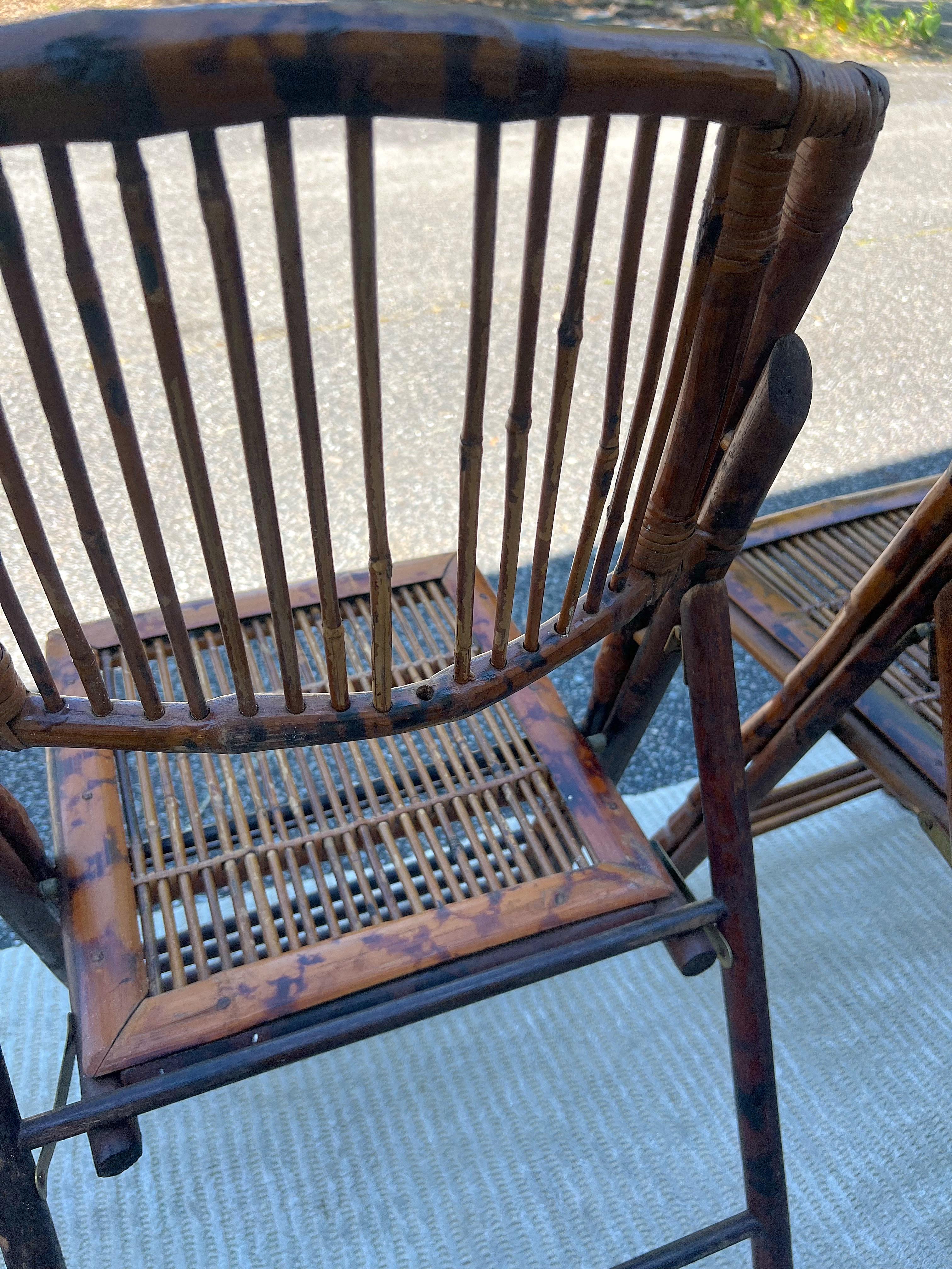 British Colonial style burnt bamboo tortoise folding chairs, a set of 8.  Most are in near perfect condition.  But 2 have a missing slat on the back.  Brass hardware and very sturdy.
