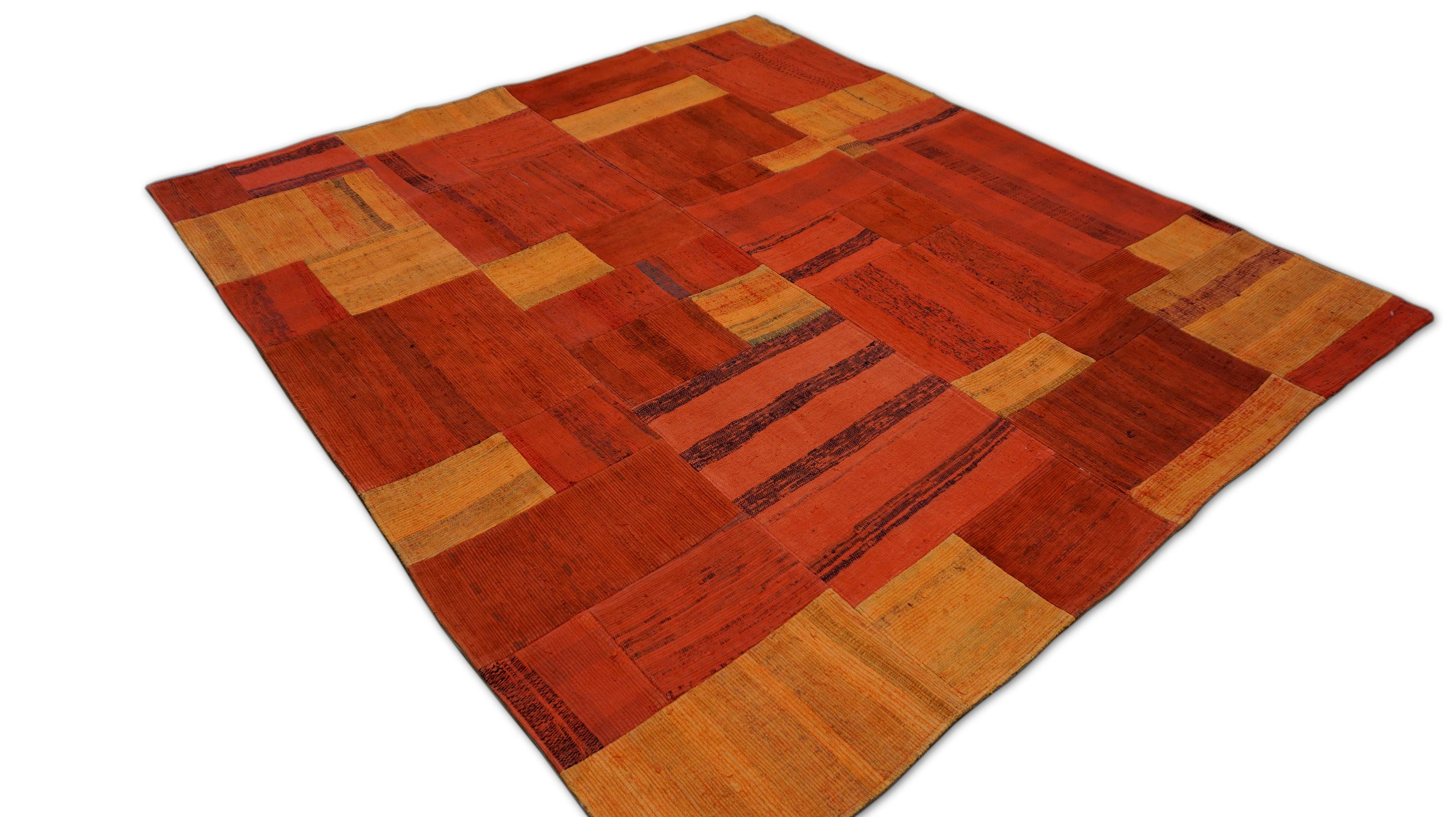 Espressione vibrante dell'eredità tessile, questo tappeto patchwork in cotone intrecciato a mano dà vita a una ricca tavolozza di rosso cotto dal sole grazie a una composizione accuratamente curata di tessuti piatti vintage riutilizzati. Tessuta e