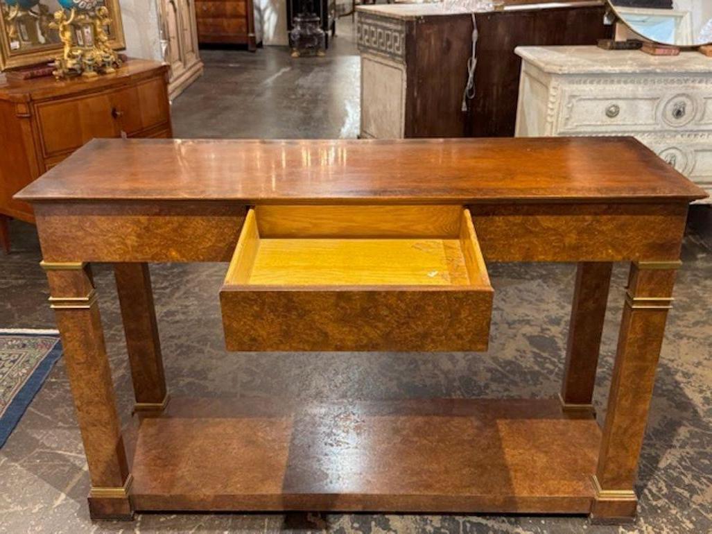 This Vintage Burr Elm Baker Furniture Empire Style Console is a classic piece of vintage furniture that exudes elegance and sophistication. Made by the renowned brand Baker,  this console combines luxury with timeless design, perfect for adding a