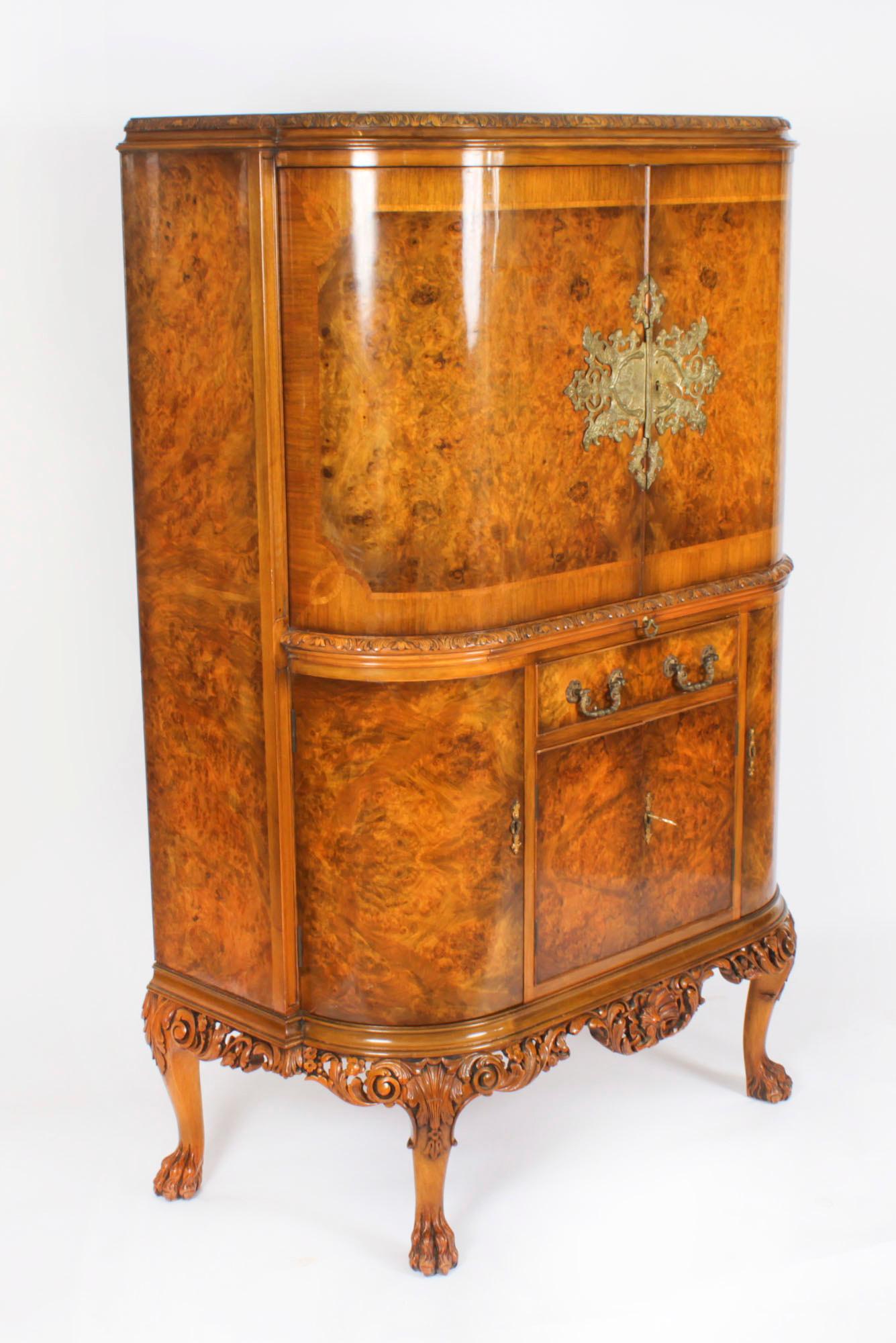 This is a superb quality vintage  burr walnut bow fronted cocktail cabinet with fitted and mirrored maple interior by Berick Furniture, dating from the mid 20th Century.

The upper part comprises a decorative carved cornice above a pair of bow doors