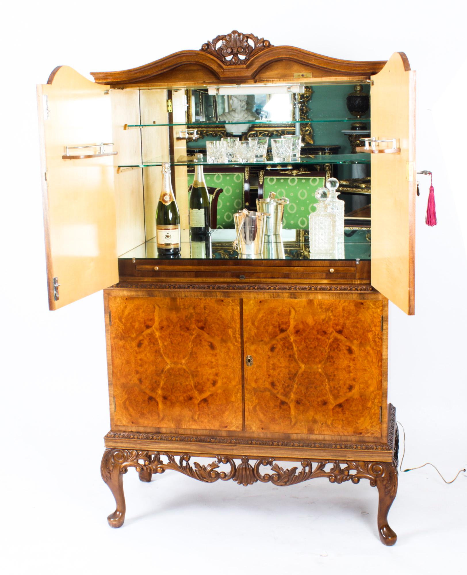 This is a fantastic vintage burr walnut cocktail cabinet with fitted and mirrored interior and ormolu mounts, dating from the mid 20th Century.

The upper part comprises a pair of doors that open to reveal a striking fitted mirrored and maple