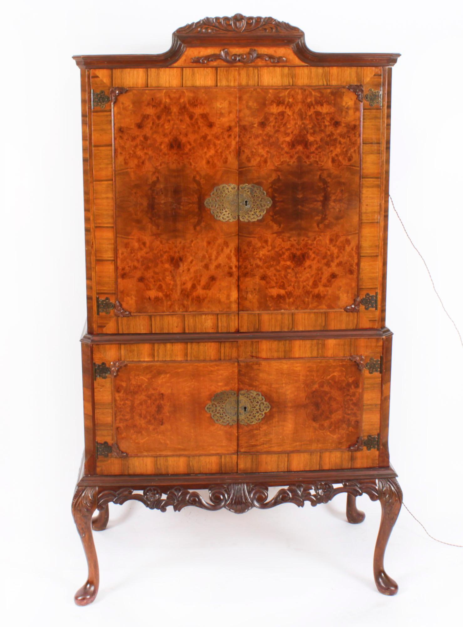 This is a fantastic vintage  burr walnut cocktail cabinet with fitted and mirrored maple interior, dating from the mid 20th Century.

The upper part comprises a decorative carved cornice above a pair of doors with decorative hinges and a large