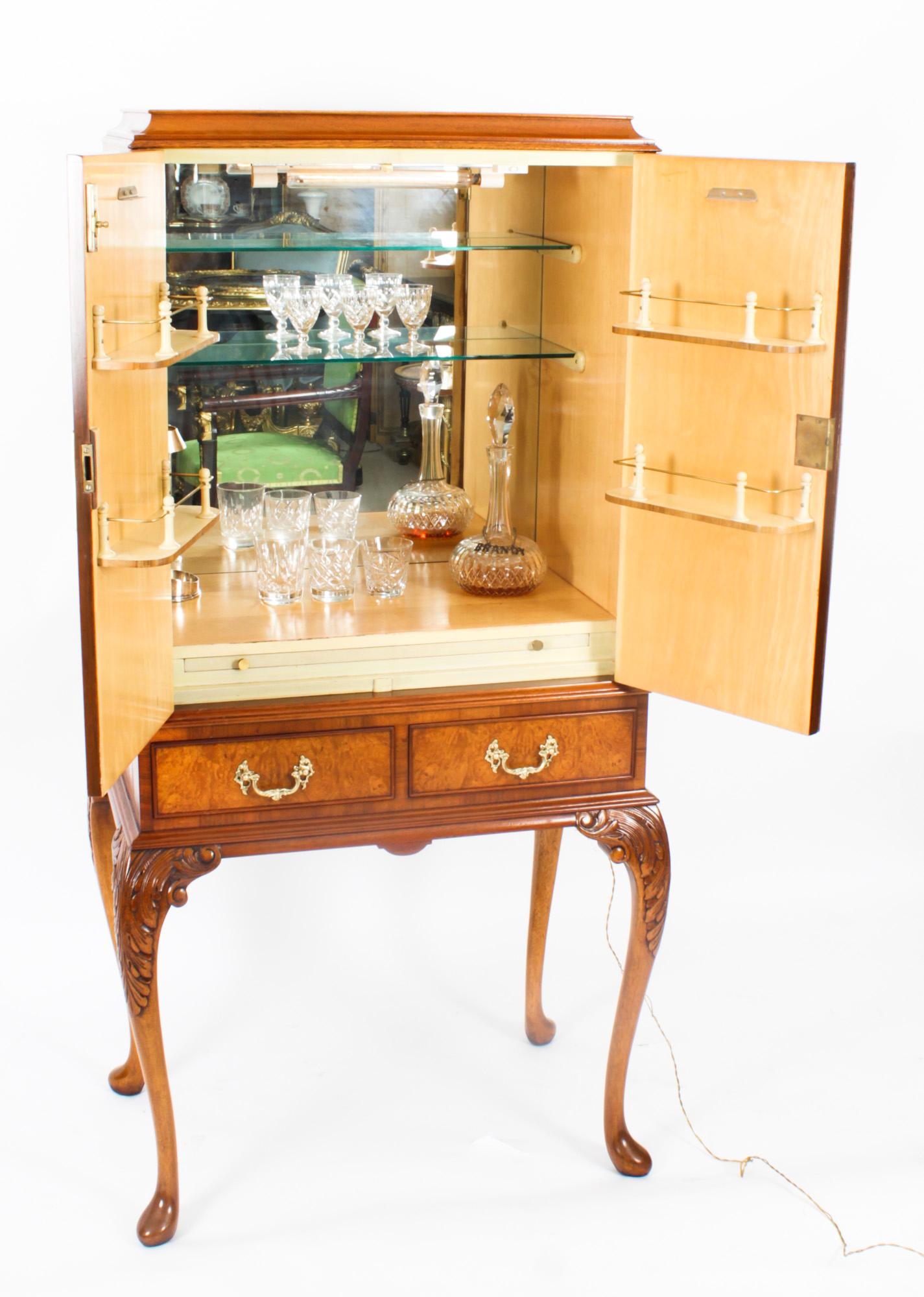 This is a fantastic vintage Queen Anne Revival burr walnut cocktail cabinet with wonderful hand carved decoration dating from the 1930's.
 
The cabinet features a carved cresting, the doors open to reveal a stunning fitted mirrored interior with a