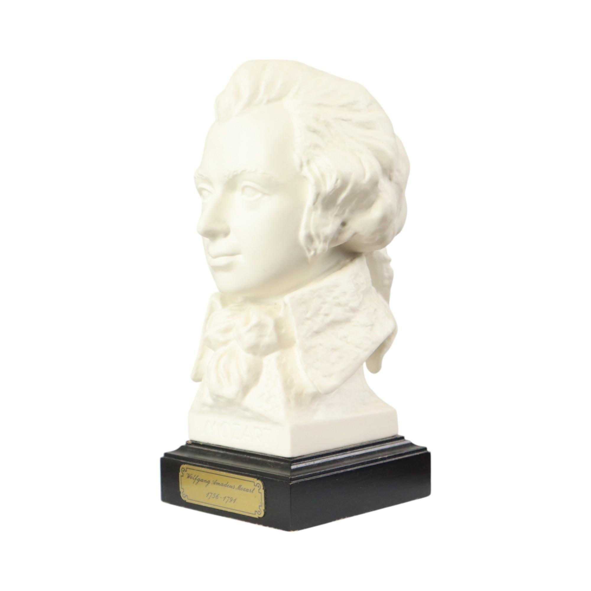 Piccolo busto vintage di Wolfgang Amadeus Mozart, realizzato in porcellana biscuit opaca, su una base quadrata in legno nero, firmato sul retro, da G. Bochmann per Goebel, Germania Ovest, fine del XX secolo, circa anni '90.

La statuetta è in